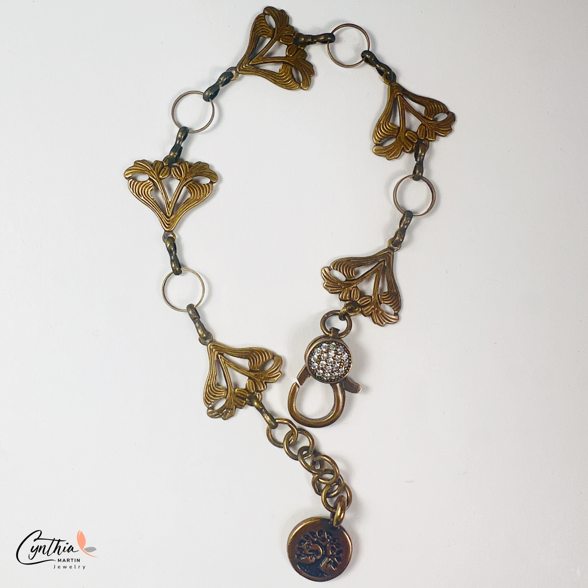 Art Nouveau-inspired jewelry set featuring delicate sun-kissed garden flowers, a bronze bonsai tree charm, and a sparkling pavé lobster clasp.