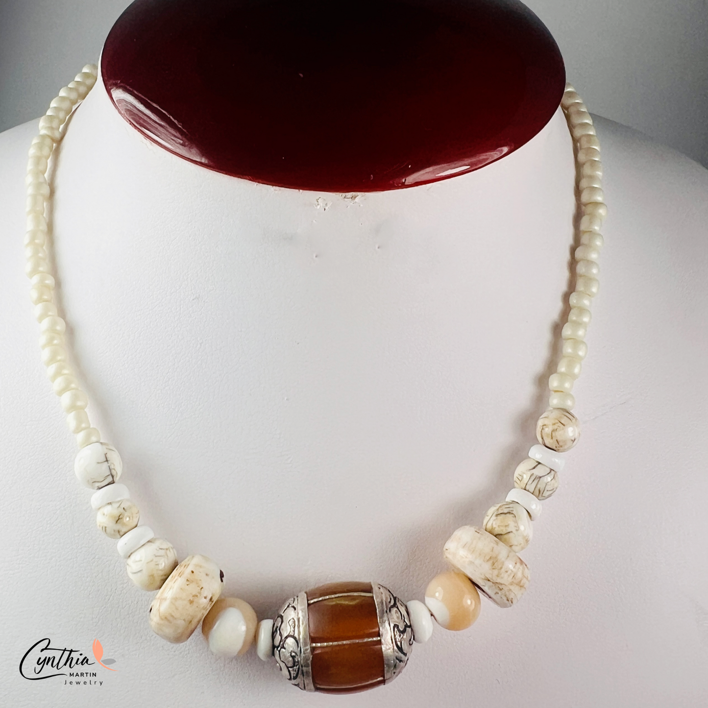 Necklace featuring an Indonesian silver and amber focal bead, accented with agate beads, natural stones, and glossy white beads, 15 inches with a 2-inch extender.