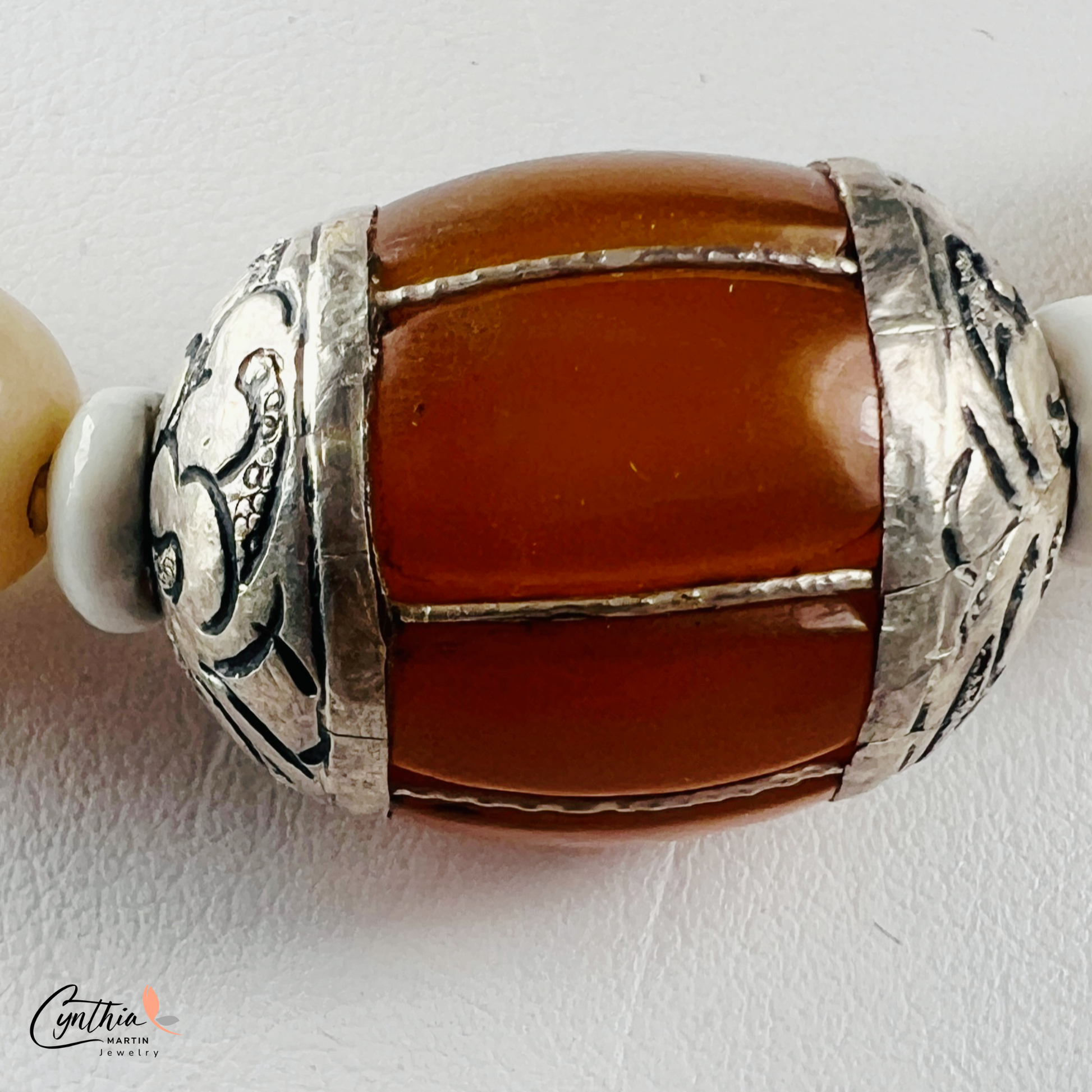 Necklace featuring an Indonesian silver and amber focal bead, accented with agate beads, natural stones, and glossy white beads, 15 inches with a 2-inch extender.