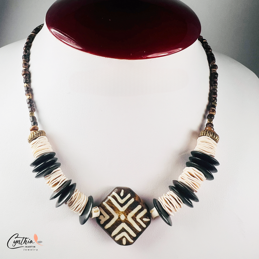 Hand-painted African tribal wooden focal bead necklace with black wooden discs, white paper beads, brown stones, and brass faceted beads, 15 inches with 2-inch extender.