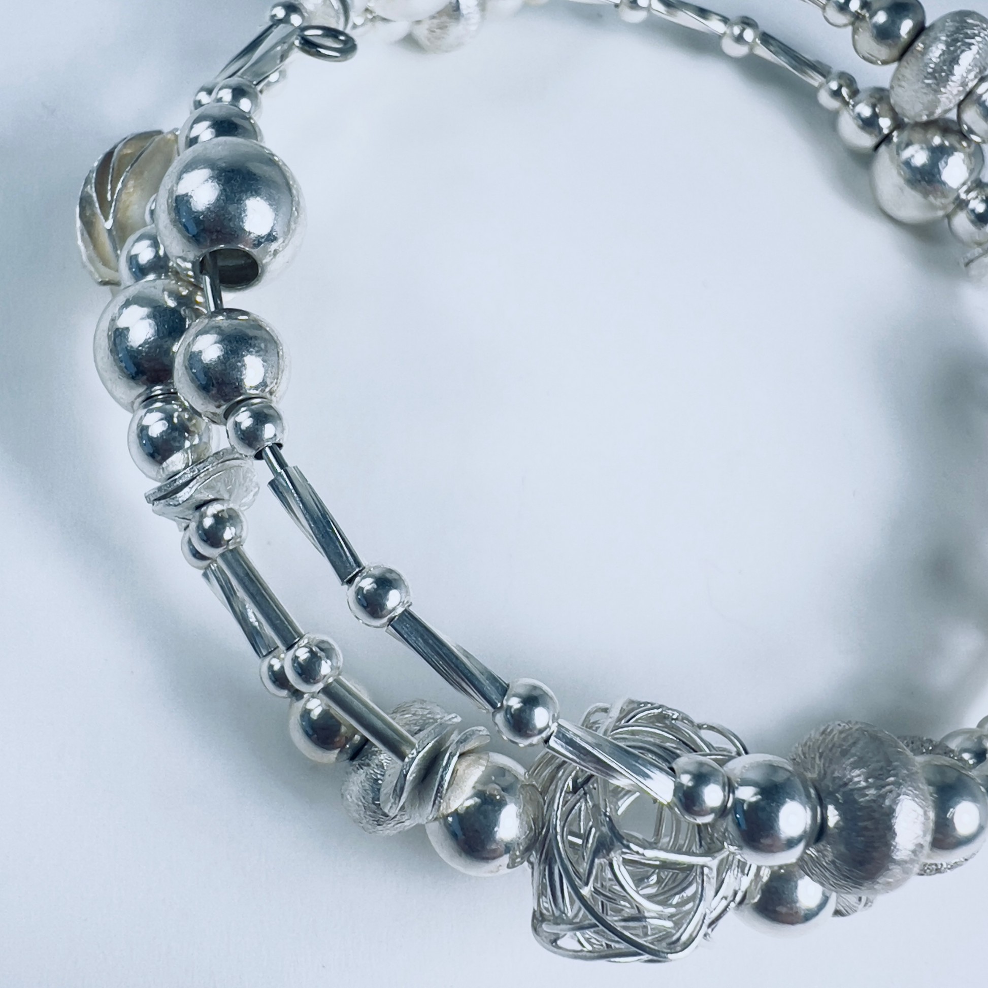 Three-wrap sterling silver bracelet with unique beads, twisted bright sterling silver beads from Thailand, and 1mm twisted rubes separating the beads.