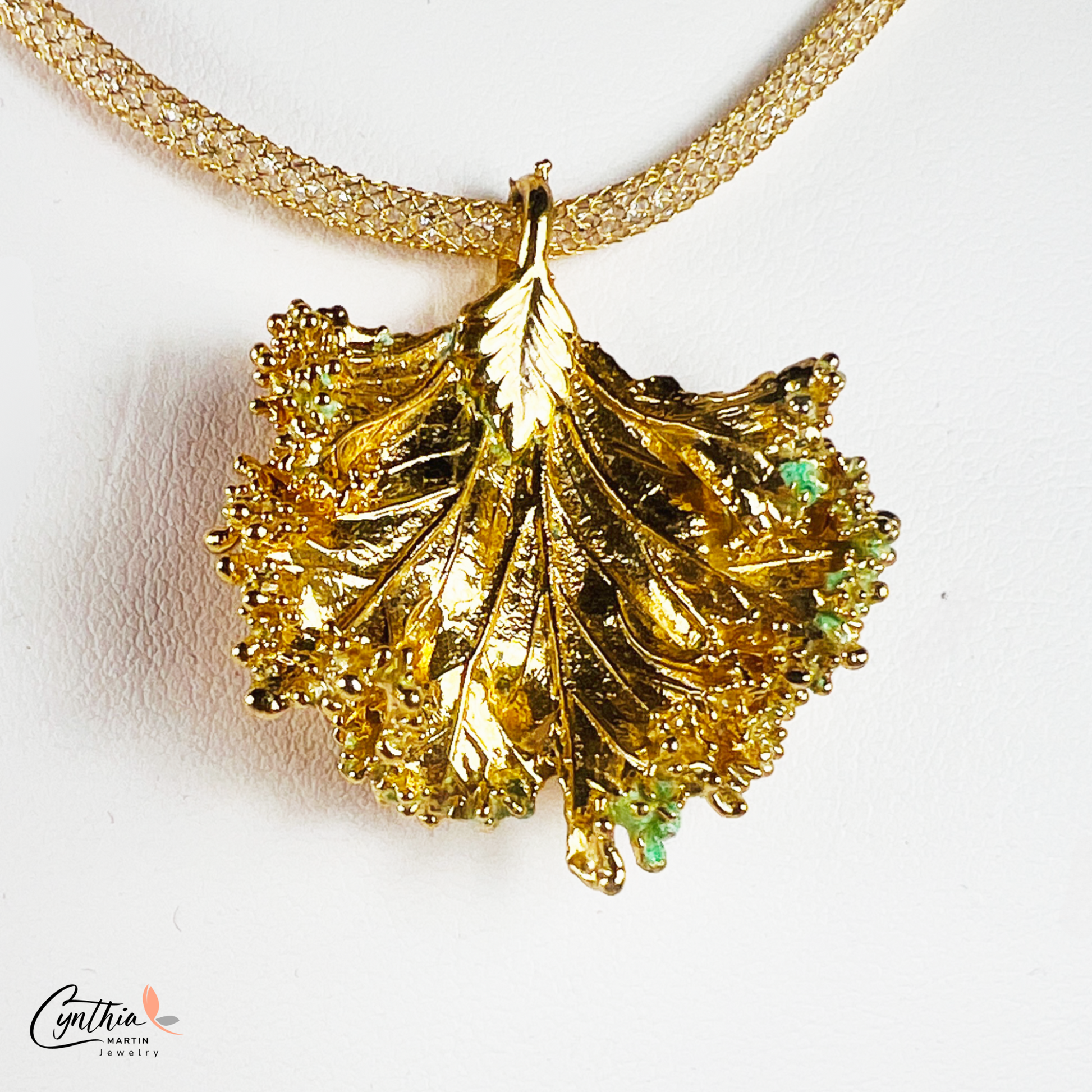 Gold pendant with a ruffled texture attached to an Italian mesh necklace, featuring embedded cubic zirconia.