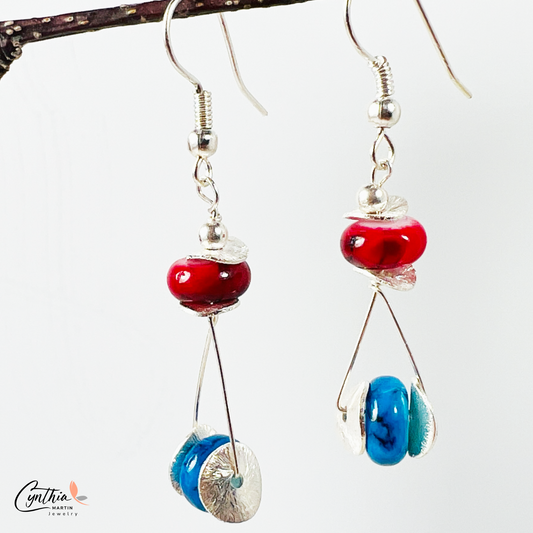 Playful earrings featuring blue beads that wink among red, adding subtle sparkle and charm.
