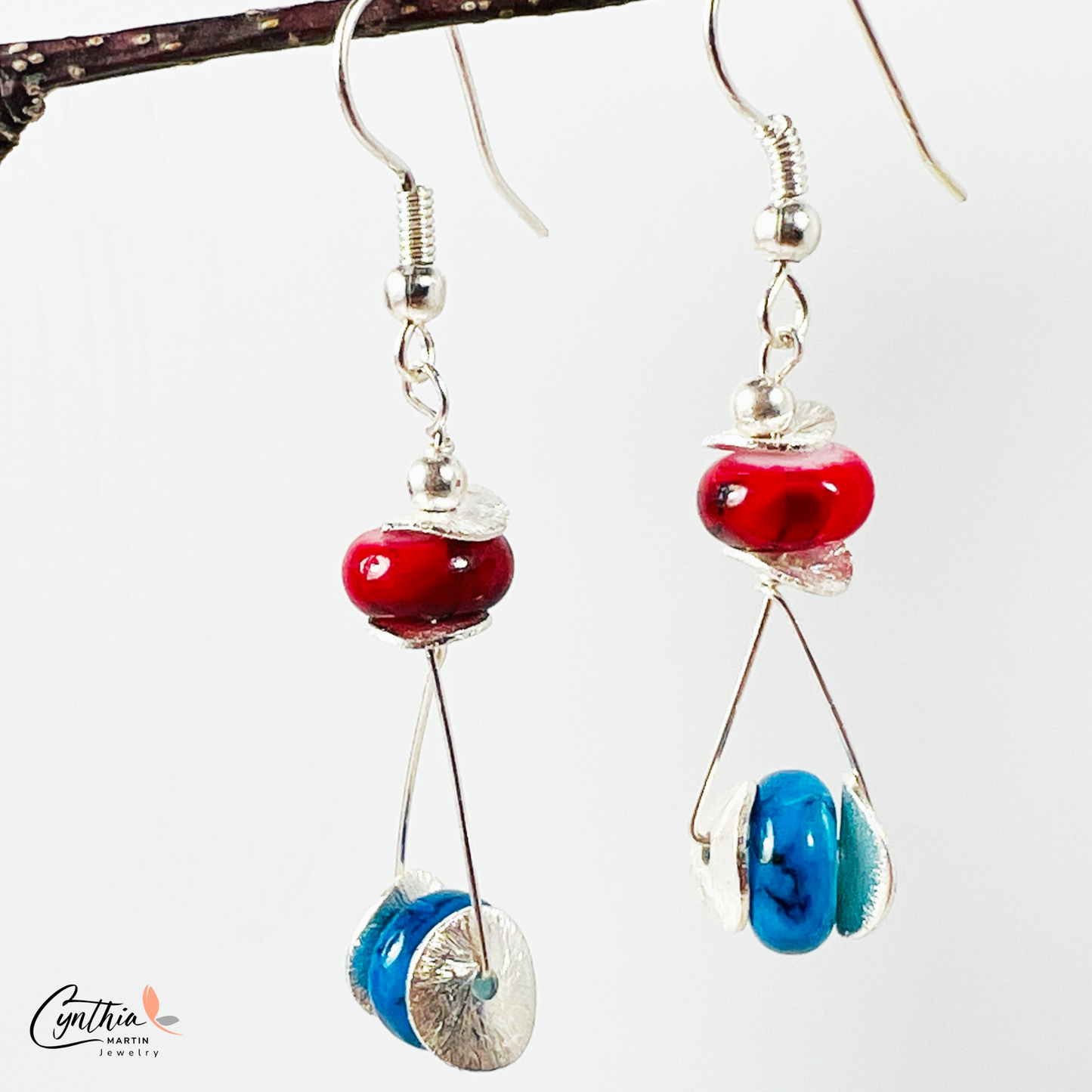 Playful earrings featuring blue beads that wink among red, adding subtle sparkle and charm.