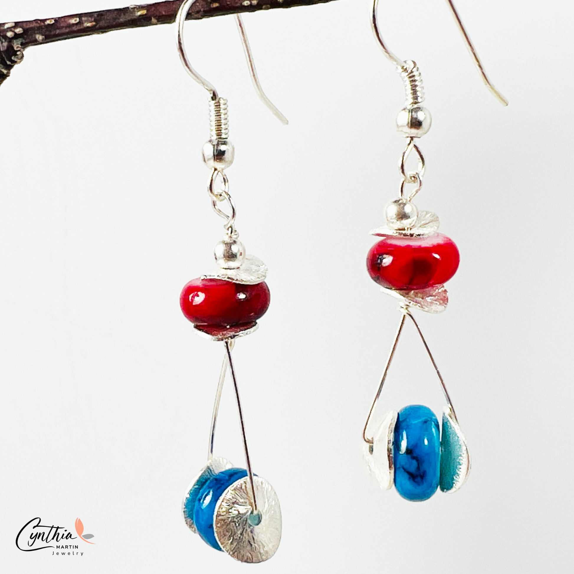 Playful earrings featuring blue beads that wink among red, adding subtle sparkle and charm.