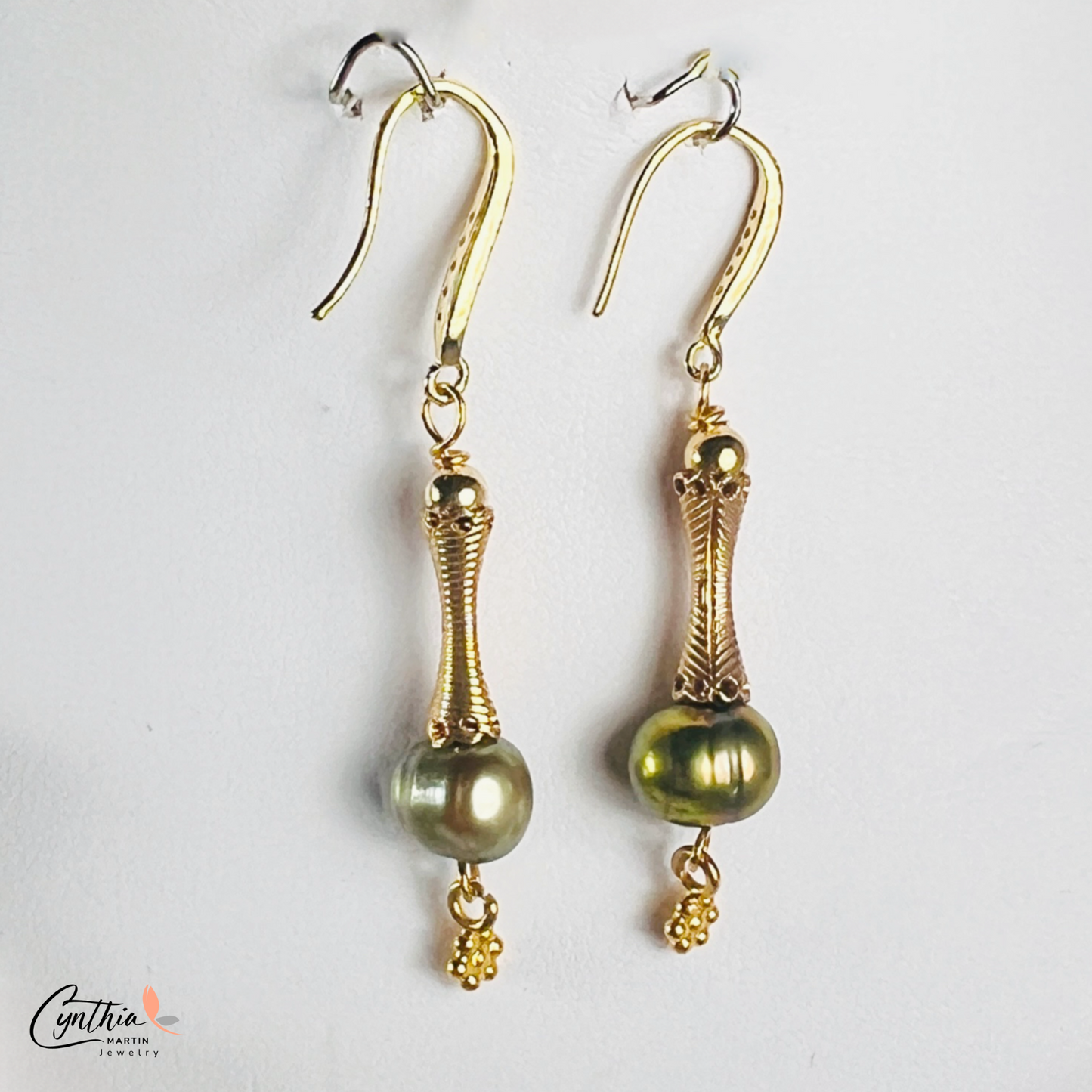 Elegant earrings featuring iridescent green pearls and gold tube spacers, perfect for casual or corporate wear.