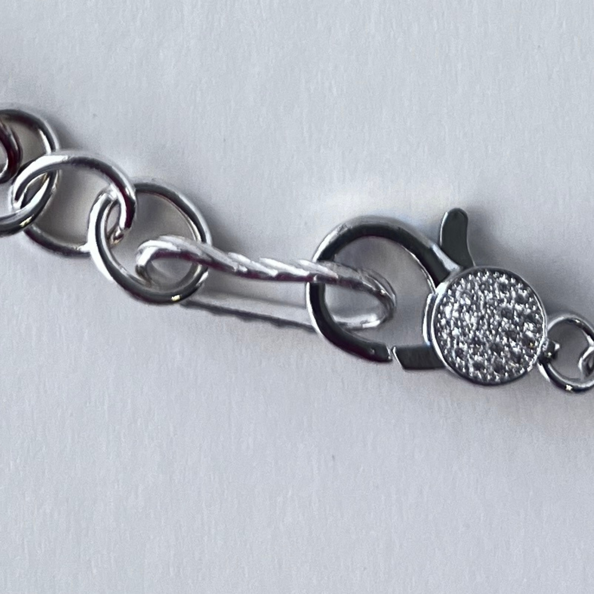 Trendy multi-link twisted chain with oval and round links in sterling silver, finished with a pave lobster clasp.