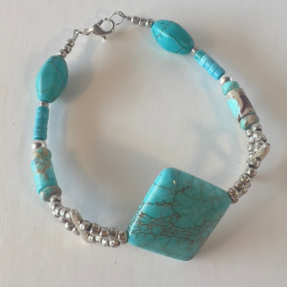 I have had this bold turquoise bead for years and years, and now it is designed on the perfect bracelet. The traditional silver and turquoise have several unusual shapes of turquoise that say 'I'm special and One-of-a-Kind'. Silver metal, wrist size 8 in.