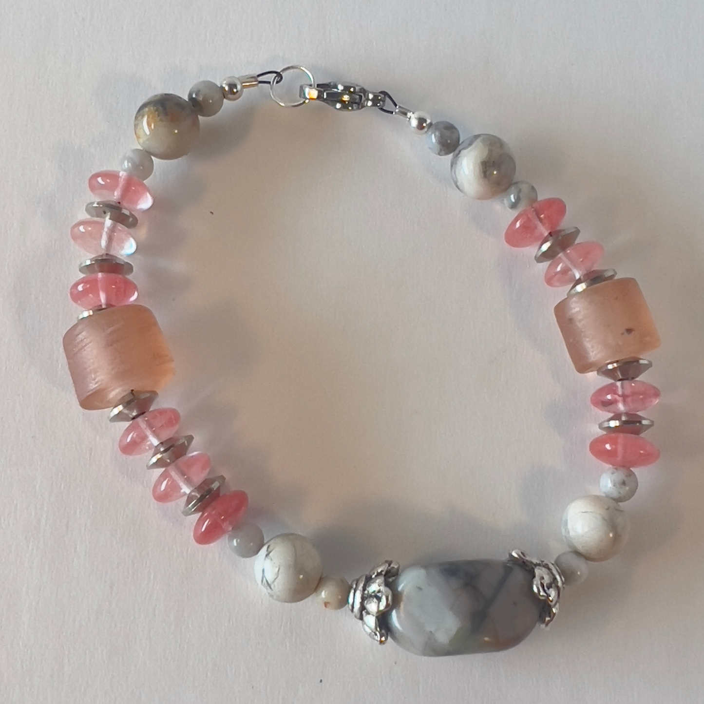 Subtle colors of grey and peach are beautiful together. Whispers soft and dainty. Silver bead caps top this sweetness off. Silver metal, wrist size 7 1/4 in.