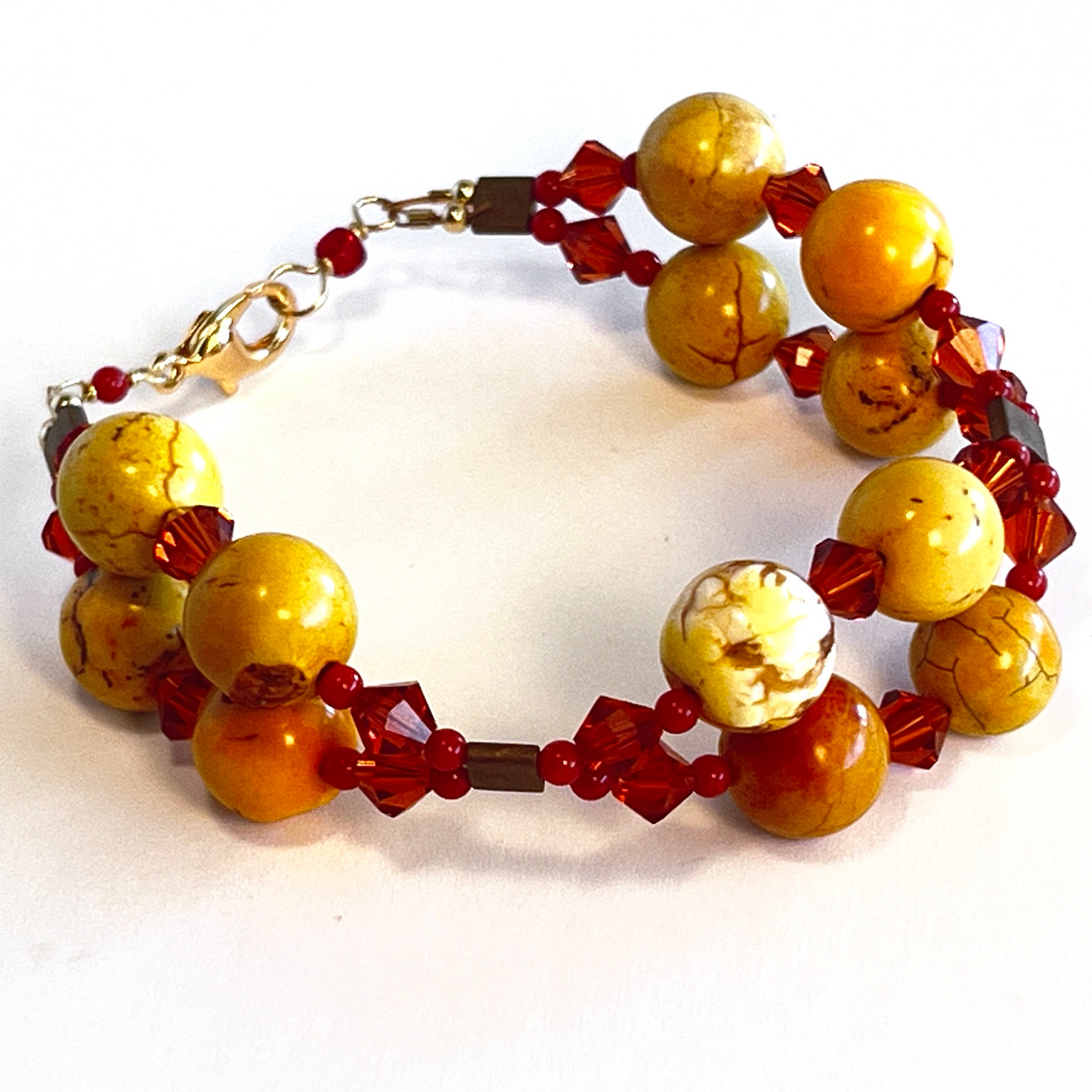 Double-strand bracelet featuring orange calcite stones paired with large red bicone beads, secured with a lobster clasp