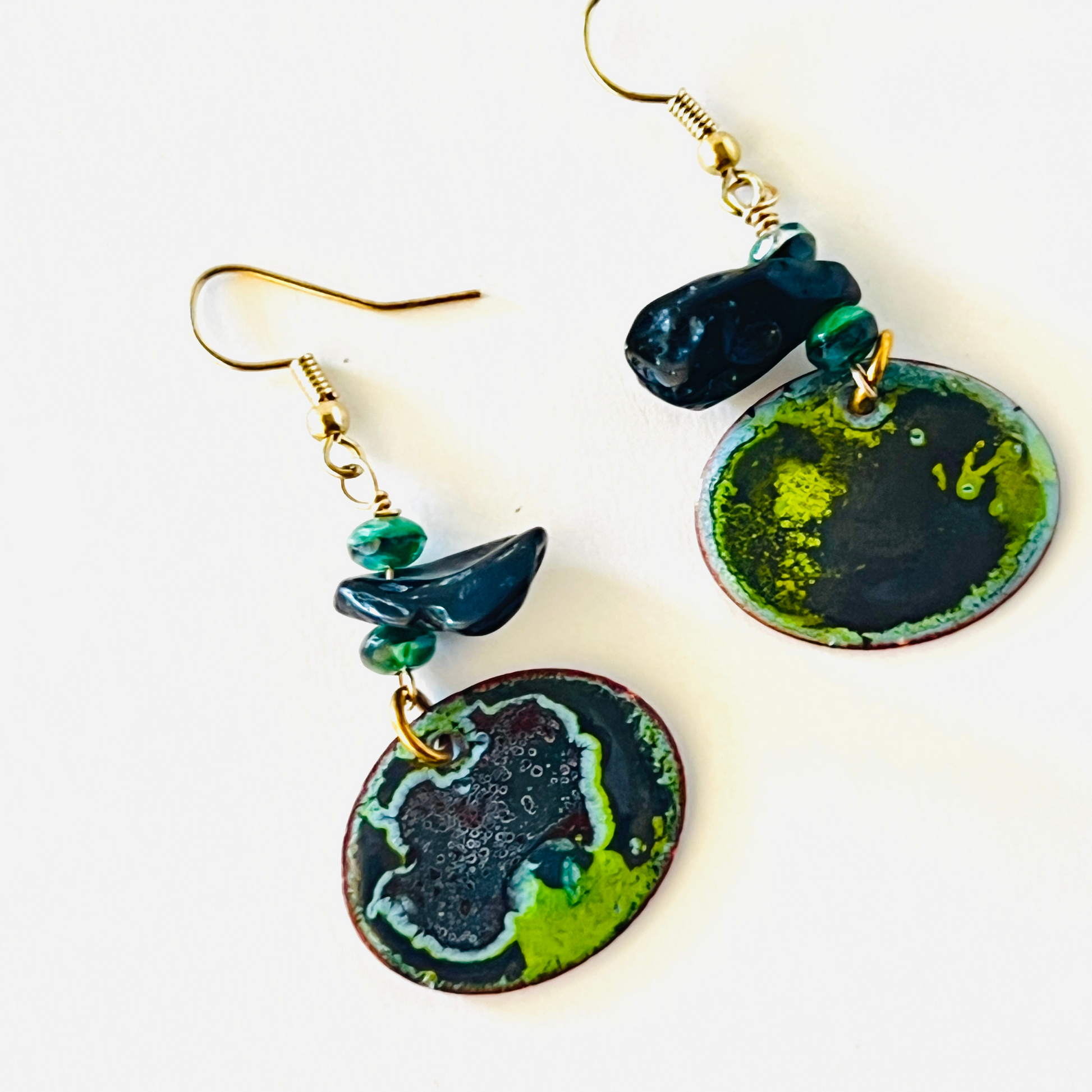 Unique torch-fired enamel earrings in black and green, hanging on gold vermeil ear wires.