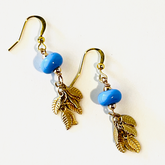 Periwinkle blue earrings with tiny gold leaf clusters, hanging on gold vermeil ear wires.