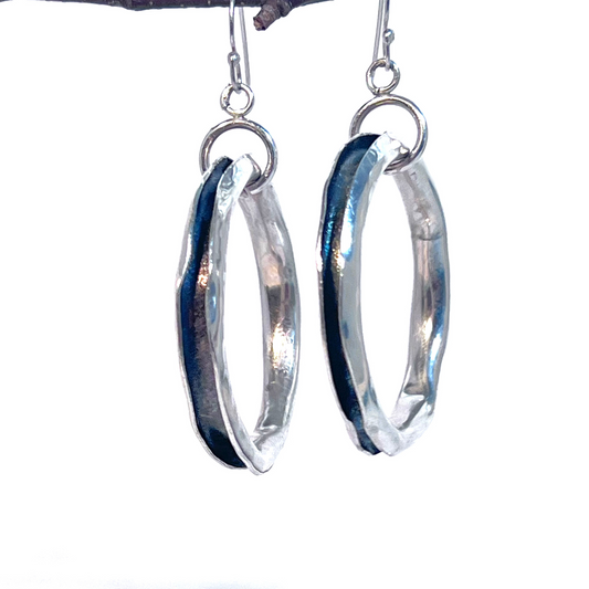 Hammered silver earrings with hollow shapes, featuring a patinated interior in blue and purple tones, and handmade ear wires.