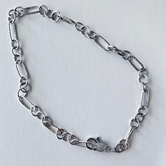 Trendy multi-link twisted chain with oval and round links in sterling silver, finished with a pave lobster clasp.