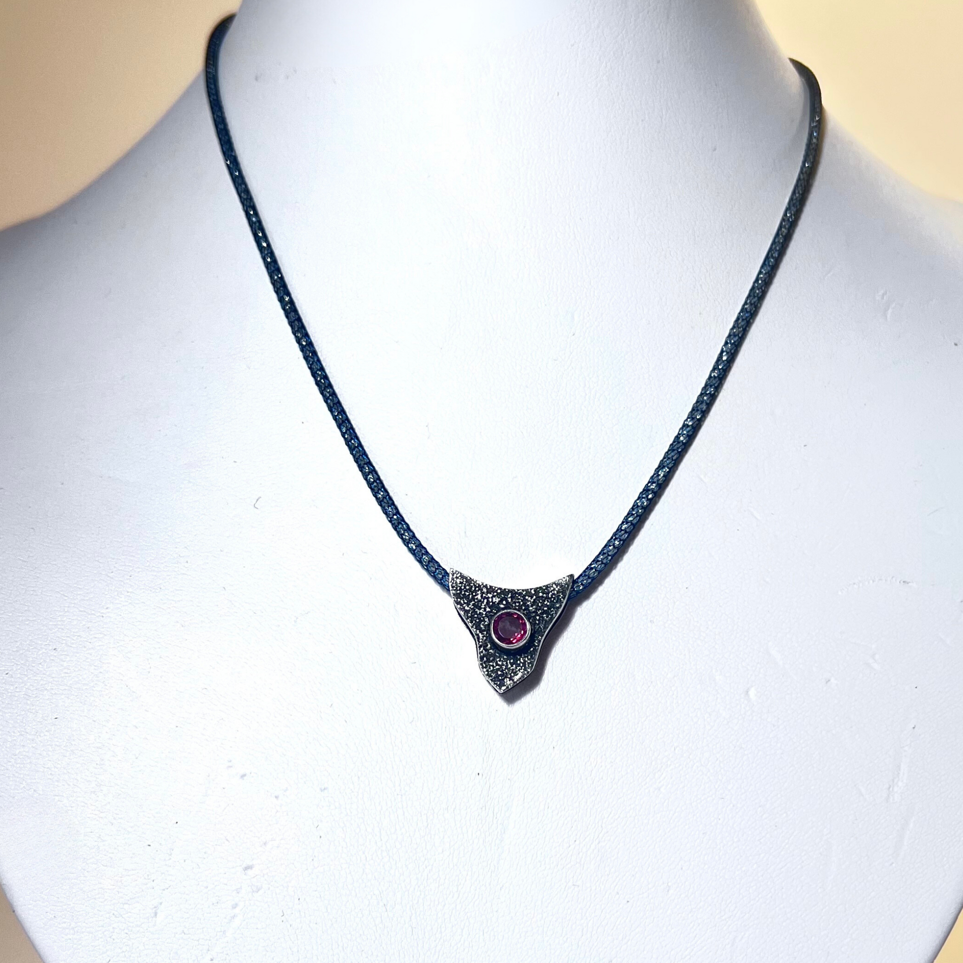 Sterling silver pendant with volcanic texture and ruby CZ center on 16-inch Italian mesh necklace. Handcrafted, elegant, and designed to enhance natural beauty and femininity.