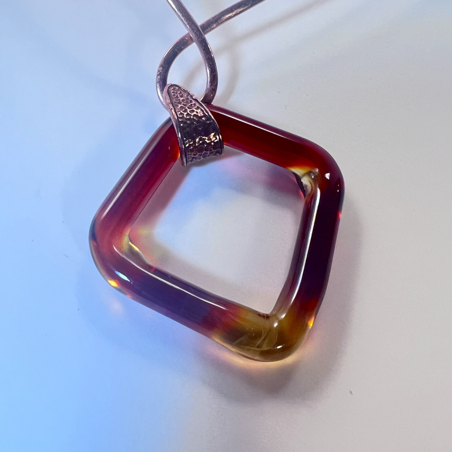 Copper neck collar holding amber square blown glass pendant by Wisconsin artist Tammy Rae, blending artistry with craftsmanship.