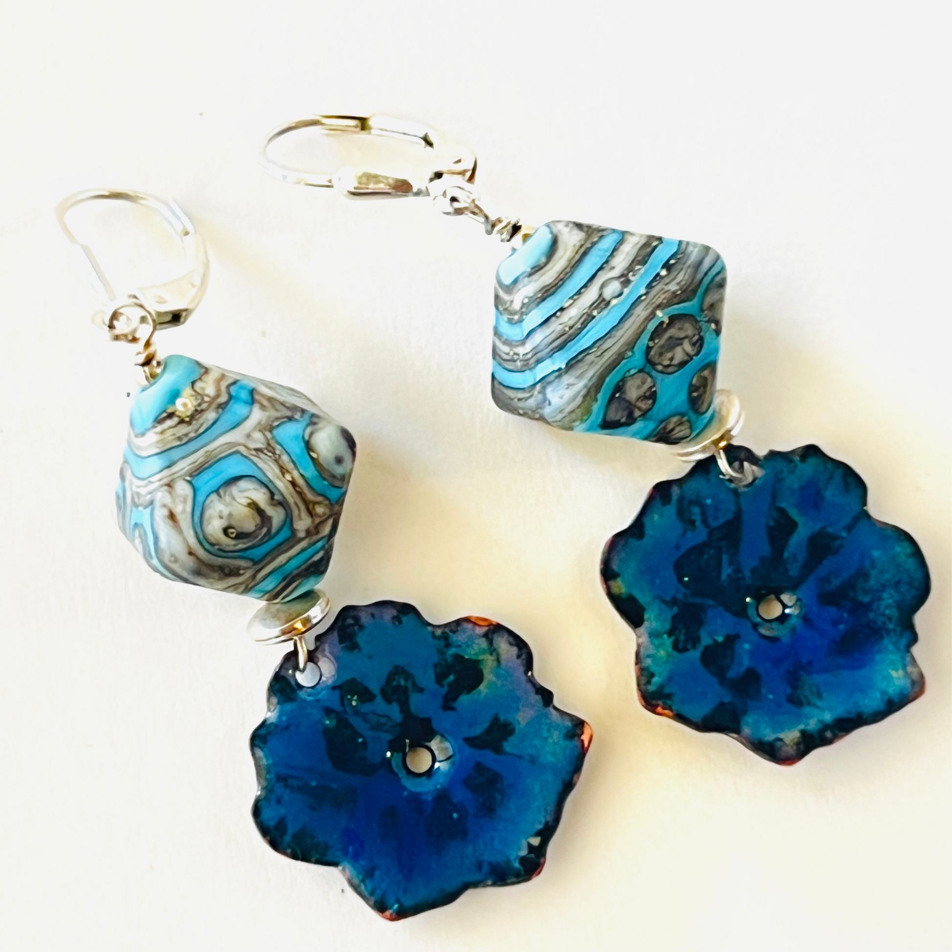 Handmade ceramic and blue flower earrings by Tucson local artist Tennessa McLean, featuring porcelain beads with molten glass designs and torch-fired flowers.