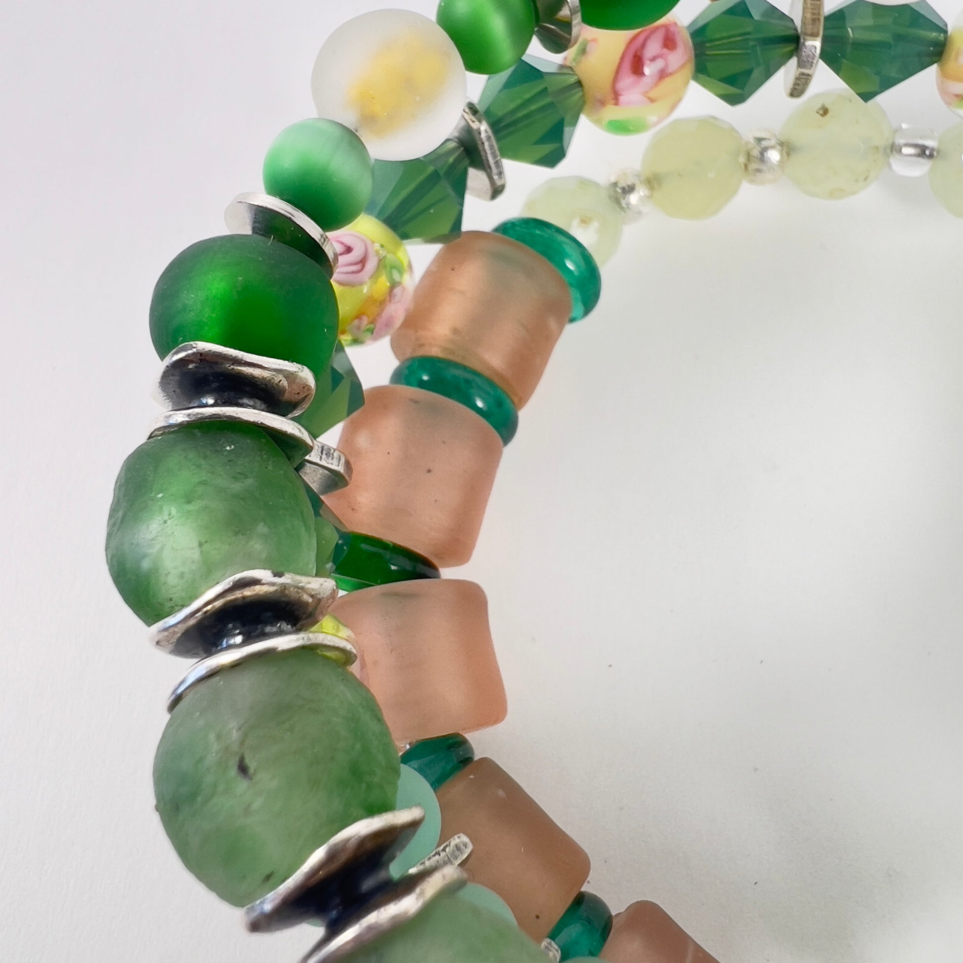 Multi-wrap bracelet featuring peach and green beads, sterling silver spacers, green cat-eye 4mm beads, sparkling transparent crystals, and 4mm beads with pink flower designs.