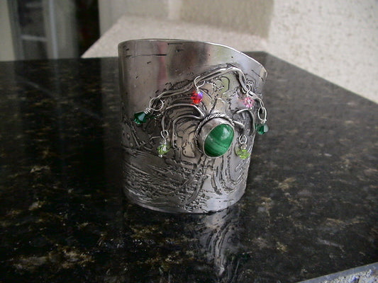 Sterling silver cuff bracelet featuring a tree of life design surrounded by snow-capped mountains, with a coral stone setting.