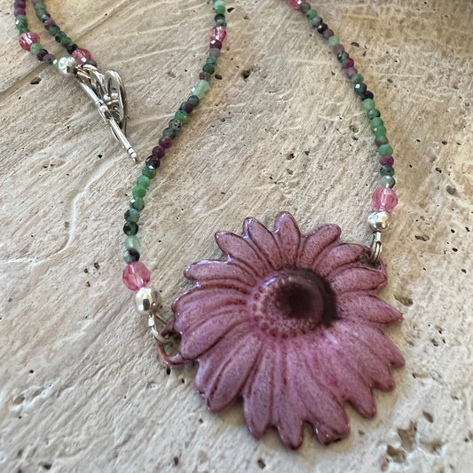 A 16-inch faceted tourmaline necklace with a vibrant enamel daisy pendant.