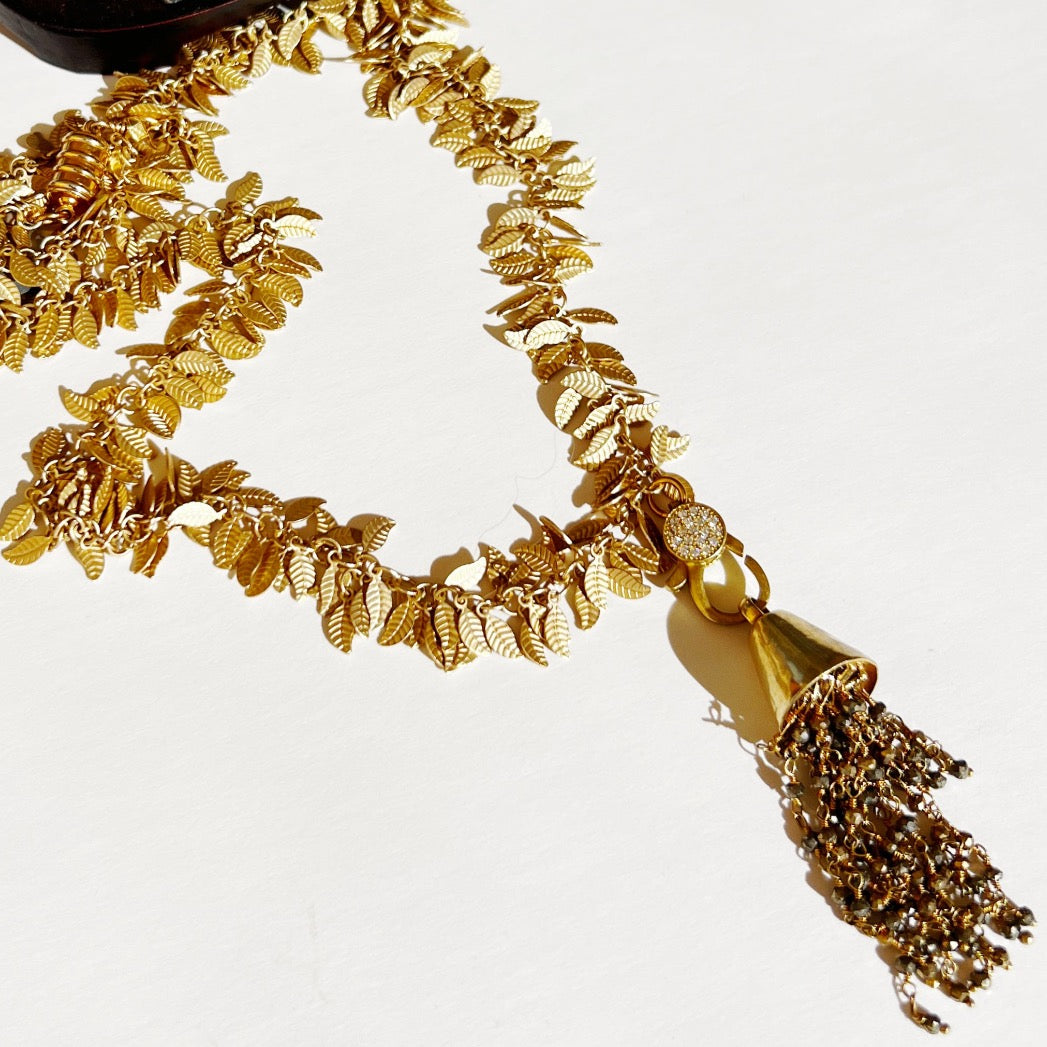 Statement gold necklace with Middle Eastern flair, featuring a tassel adorned with small gemstones and gold accents.