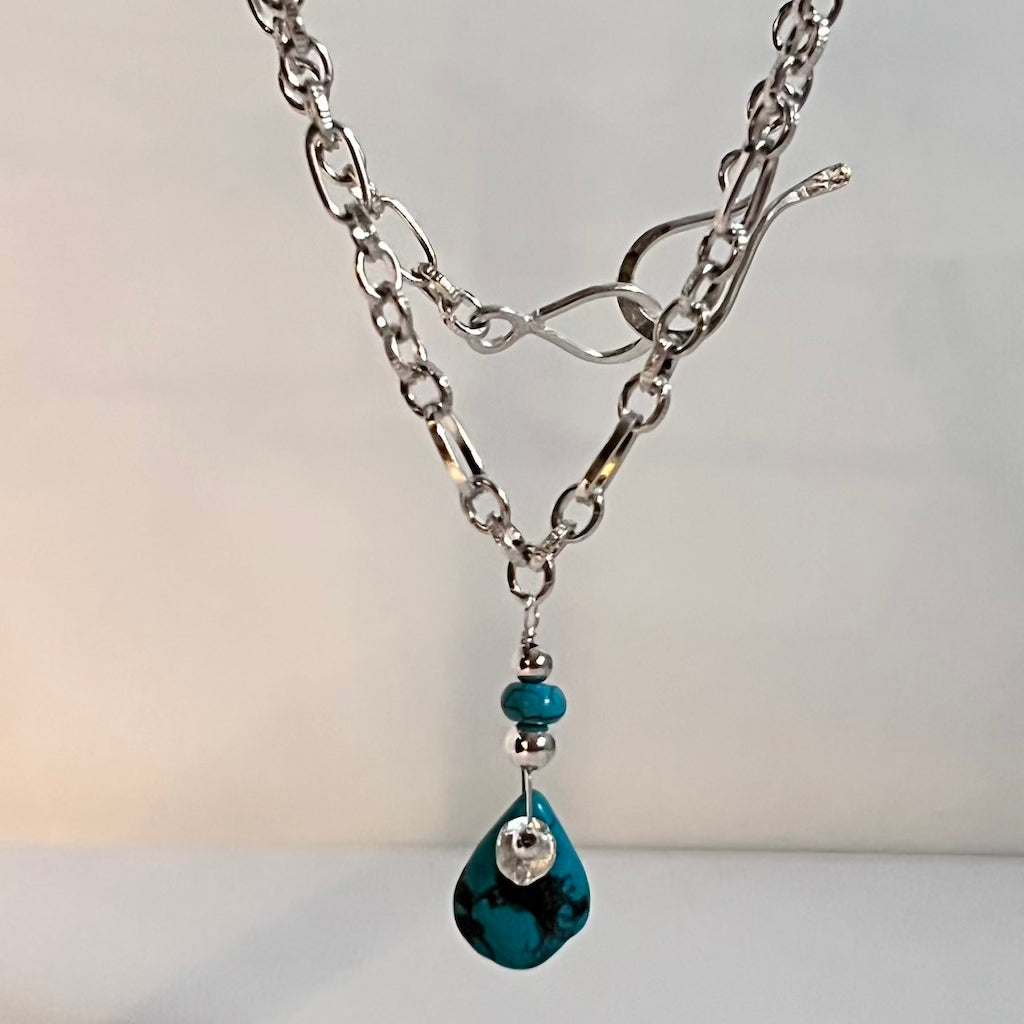 Authentic pear-shaped turquoise pendant dangling from a medium-link sterling silver chain.