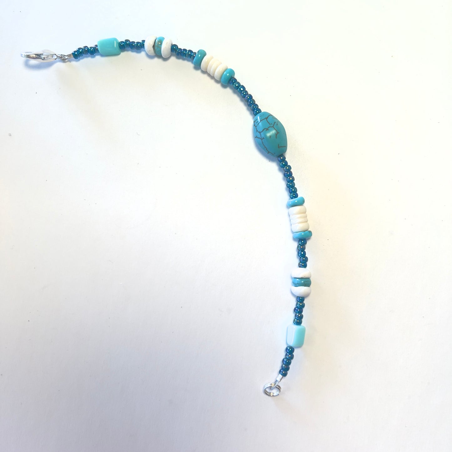 Single-strand bracelet featuring turquoise beads in various sizes, accented with blue seed beads, secured with a lobster clasp