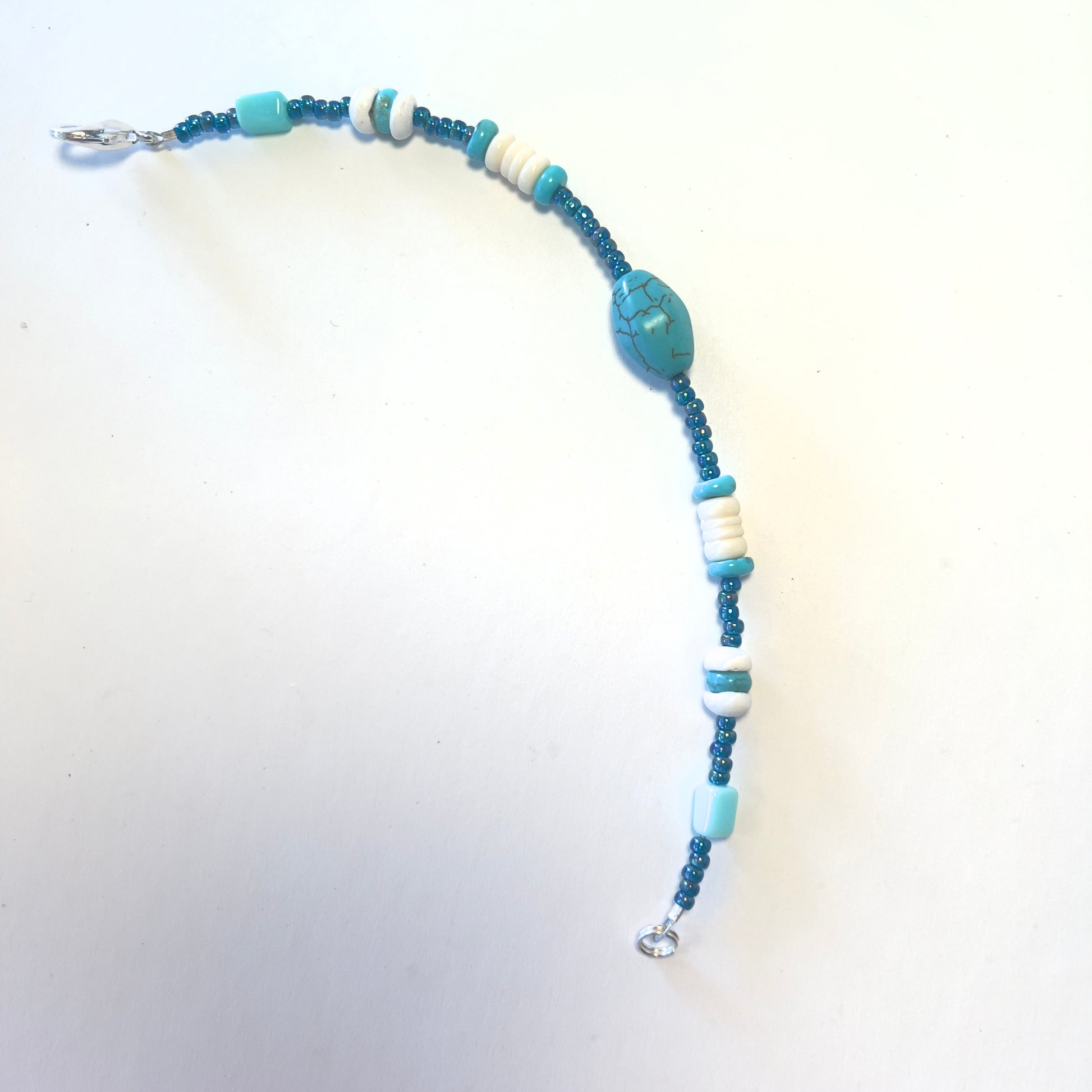 Single-strand bracelet featuring turquoise beads in various sizes, accented with blue seed beads, secured with a lobster clasp