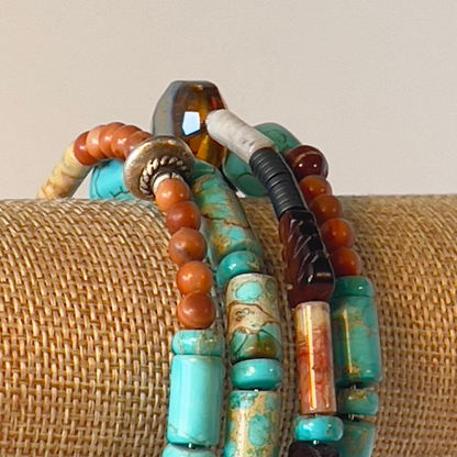 This is a naturally elegant wrap bracelet with hand-polished brilliant turquoise tubes and rondelle spacers. Designed with beautiful turquoise colors, coral, and brown and cream high-polished agate and glass. Silver metal, one size fits all.