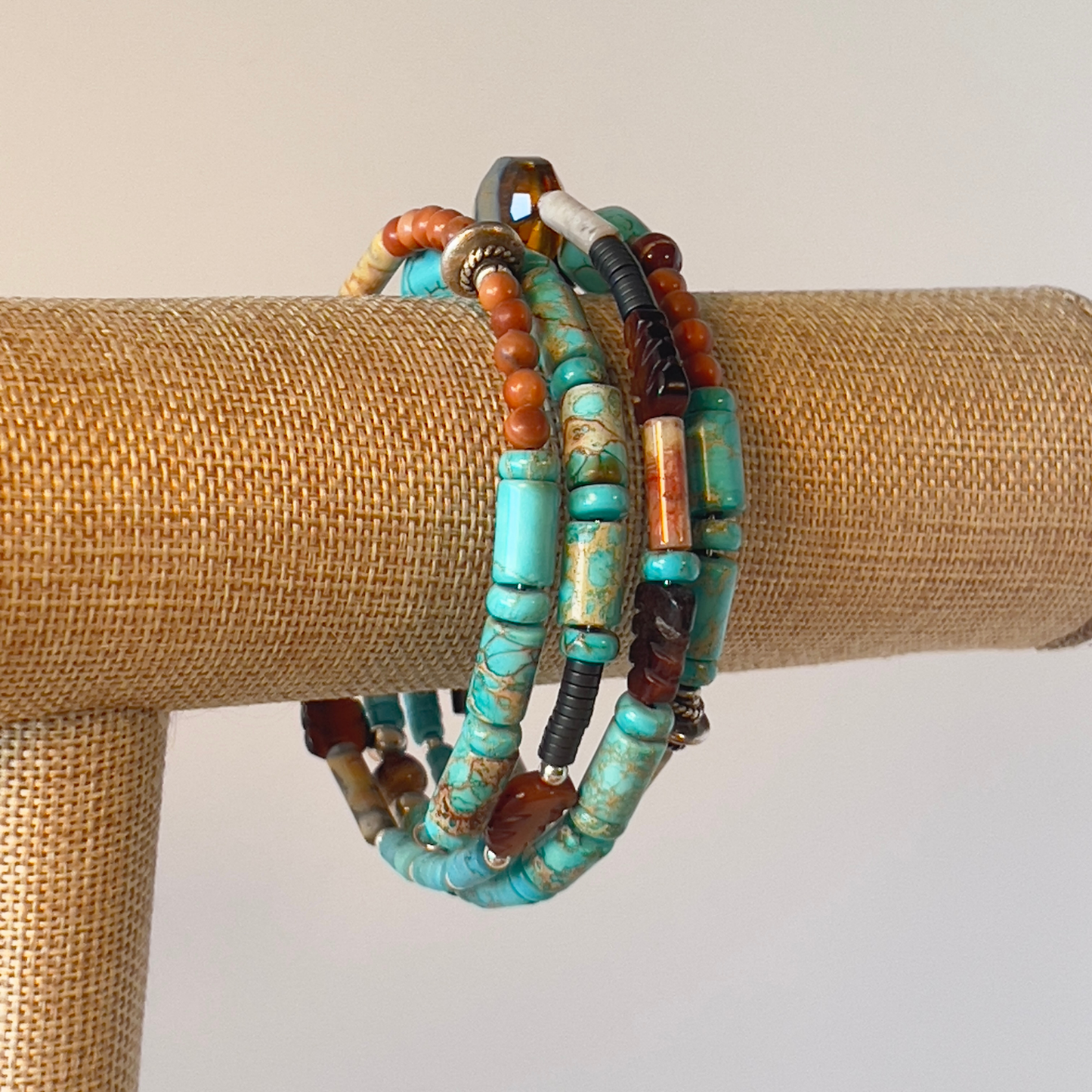 This is a naturally elegant wrap bracelet with hand-polished brilliant turquoise tubes and rondelle spacers. Designed with beautiful turquoise colors, coral, and brown and cream high-polished agate and glass. Silver metal, one size fits all.