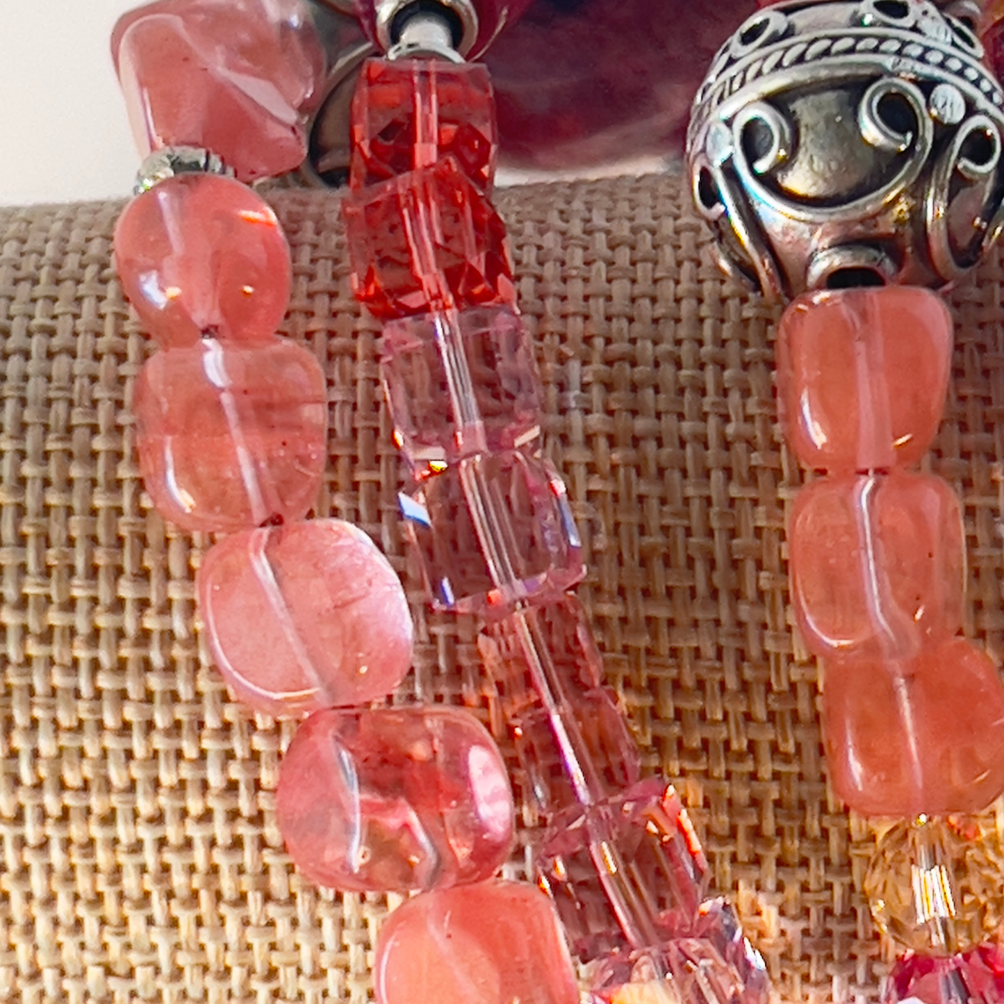 Delicate transparent cherry quartz wraps around four times in this beautiful bracelet that highlights square pink crystals and is topped off with a beautiful lavender Murano Italian glass-blown bead. Stunning with three giant Bali silver beads to take notice. Cherry quartz promotes healing chakra. Silver metal, one size fits all.