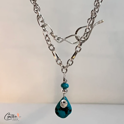 Authentic pear-shaped turquoise pendant dangling from a medium-link sterling silver chain.