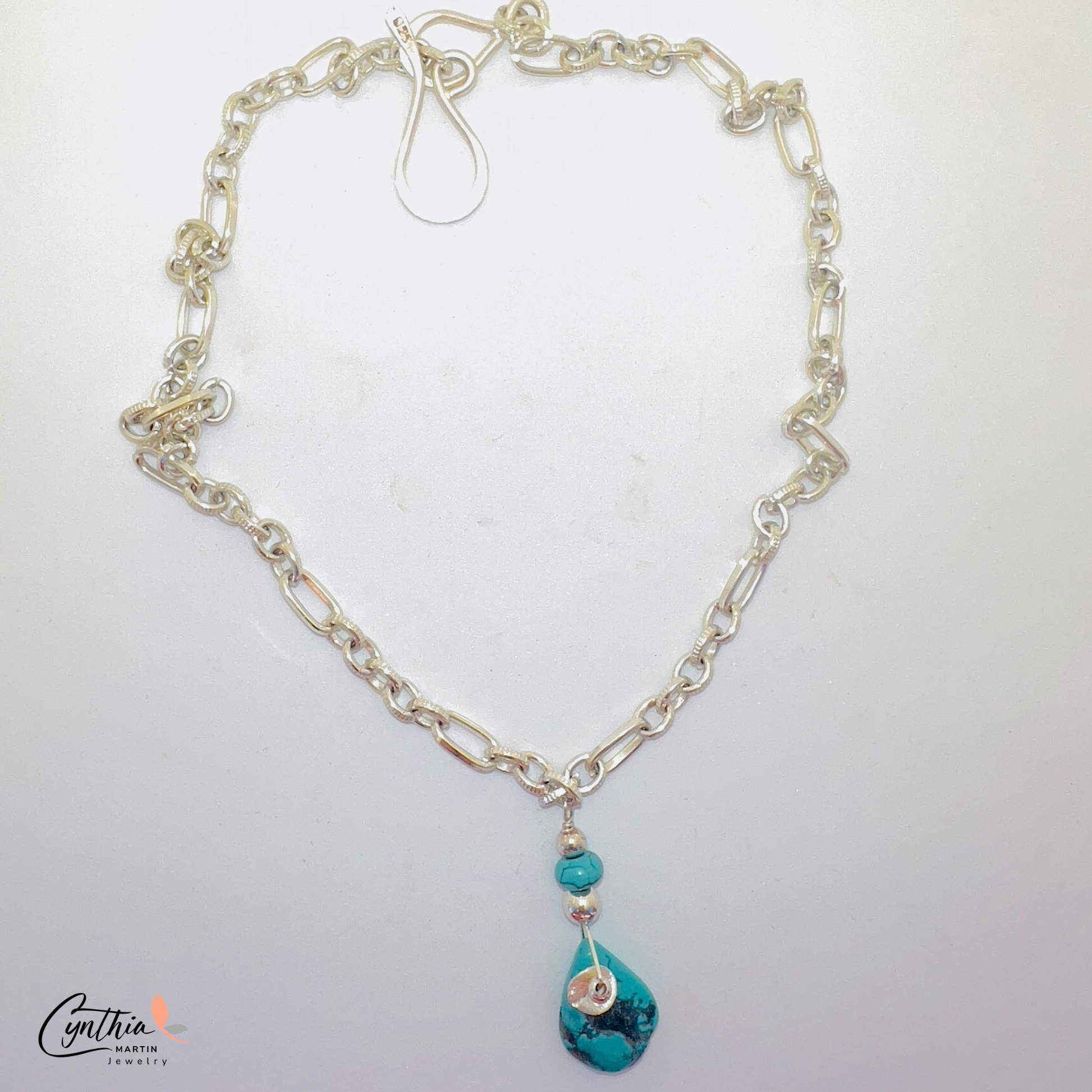 Authentic pear-shaped turquoise pendant dangling from a medium-link sterling silver chain.