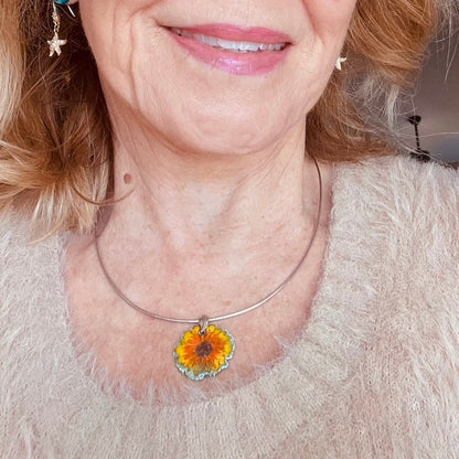 Fine silver sunflower pendant with blue enamel base, hand-painted yellow petals, and vibrant orange highlights on sterling silver omega chain.