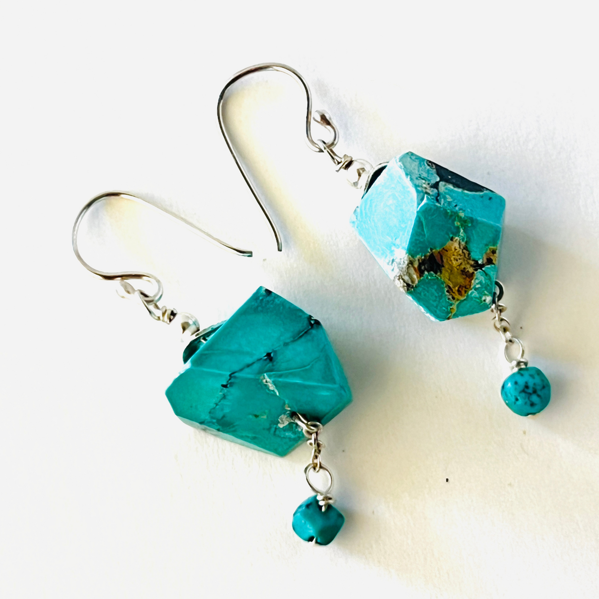 Sliced authentic turquoise nuggets hanging from French ear wires with a small nugget accent dangle on the bottom.