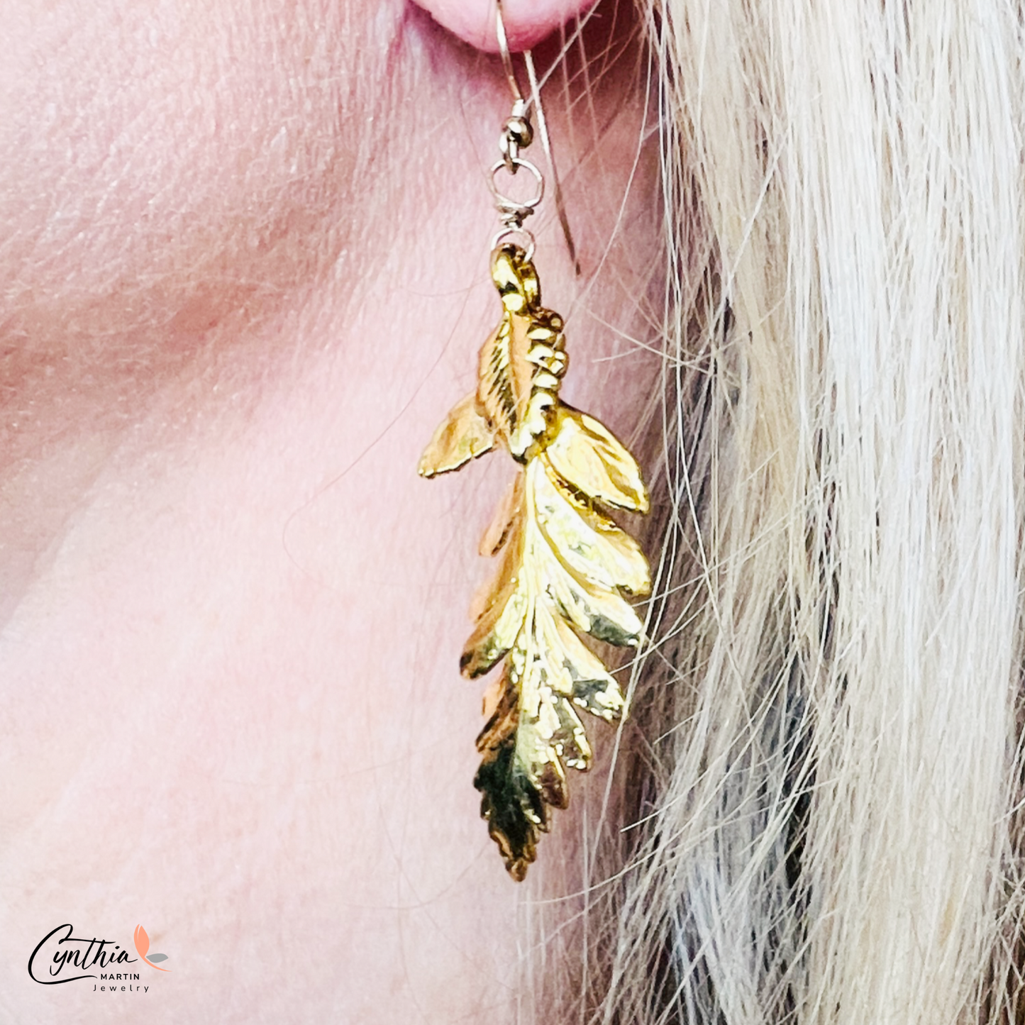 Shiny fern-shaped gold dangle earrings twinkle as they weave through hair, reflecting the essence of Mother Nature.
