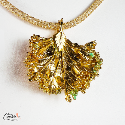 Gold pendant with a ruffled texture attached to an Italian mesh necklace, featuring embedded cubic zirconia.
