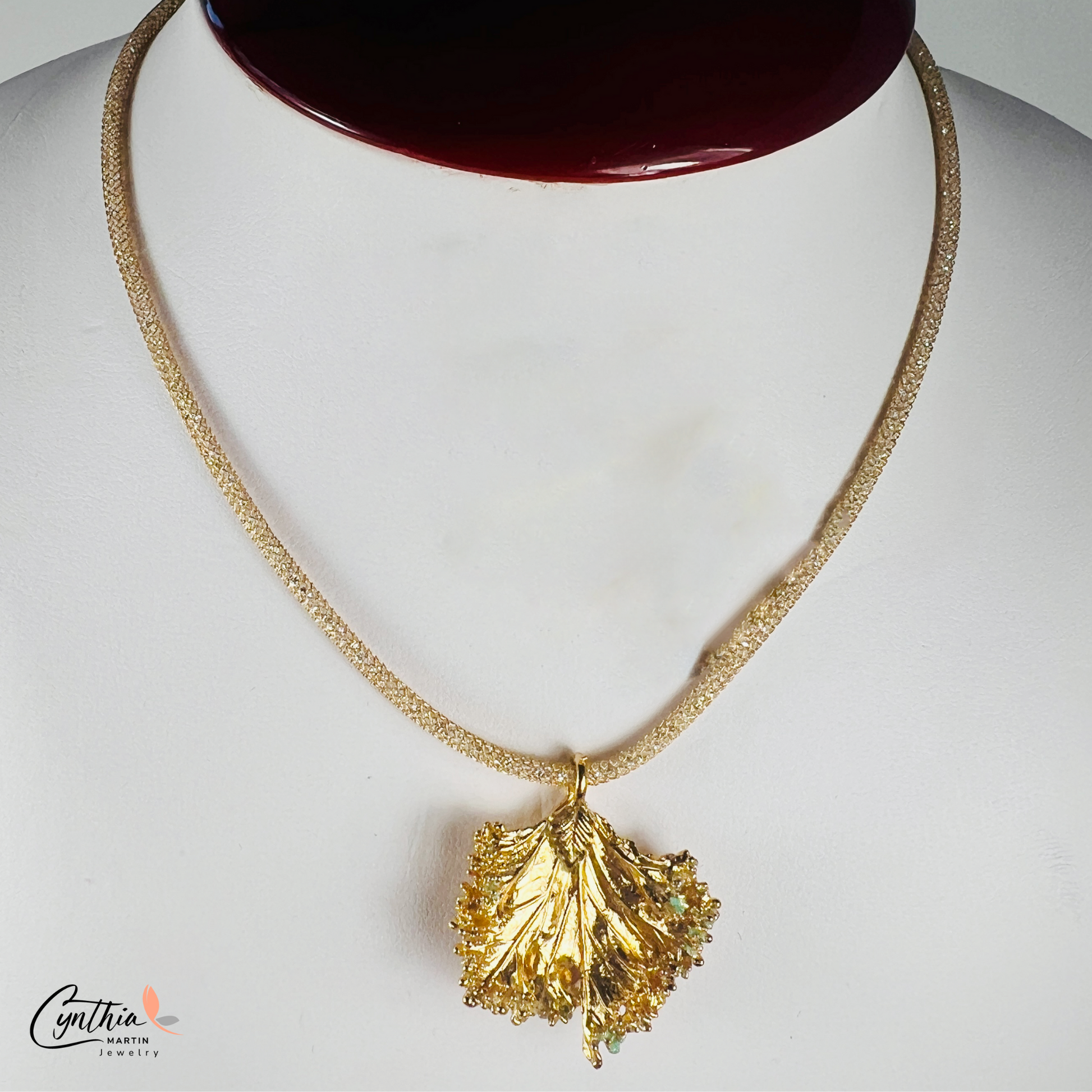 Gold pendant with a ruffled texture attached to an Italian mesh necklace, featuring embedded cubic zirconia.
