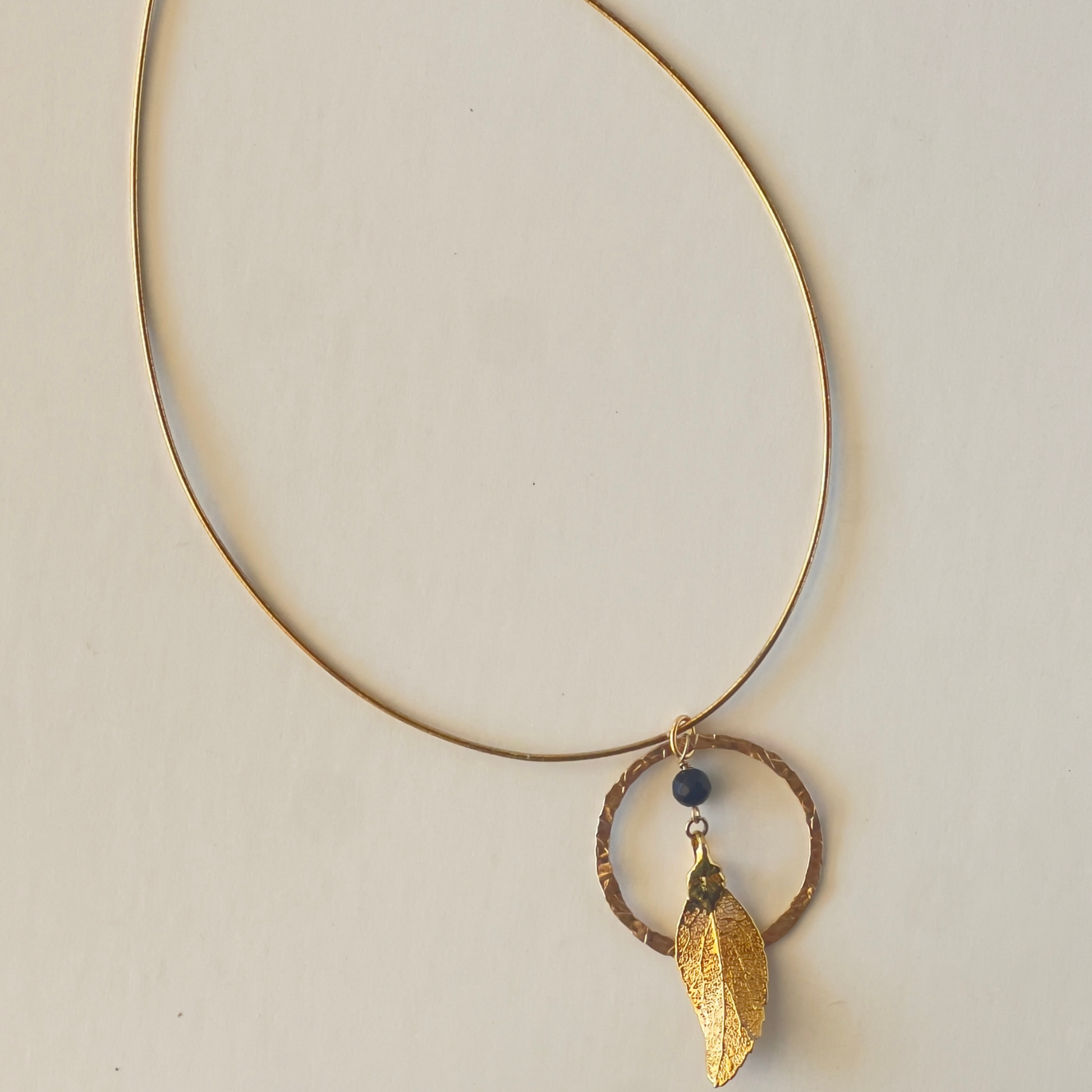 Hammered gold vermeil round loop pendant with a dangling leaf center, perfect for the stylish woman who appreciates unique jewelry.