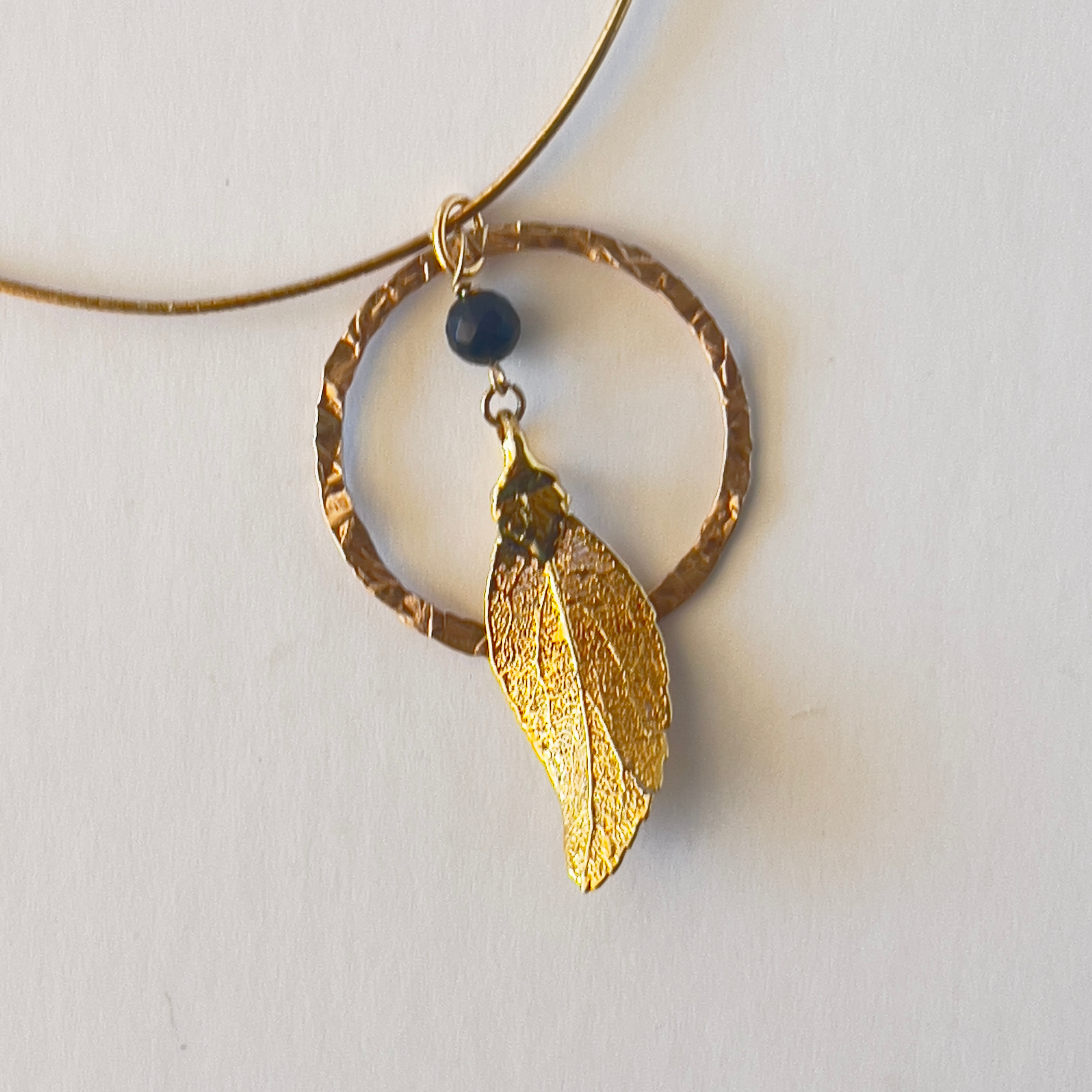 Hammered gold vermeil round loop pendant with a dangling leaf center, perfect for the stylish woman who appreciates unique jewelry.