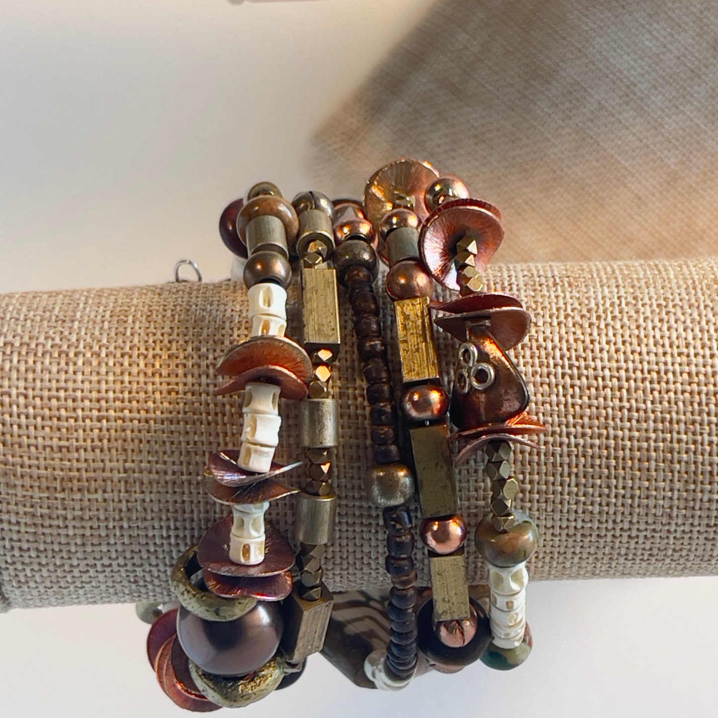 African style bracelet with hand-painted square ceramic bead, bold brass beads, cream bone spacers, square rectangle brass beads, copper round beads, and shiny textured copper flat spacers. Pair with a big copper medallion. Silver metal, one size fits all.