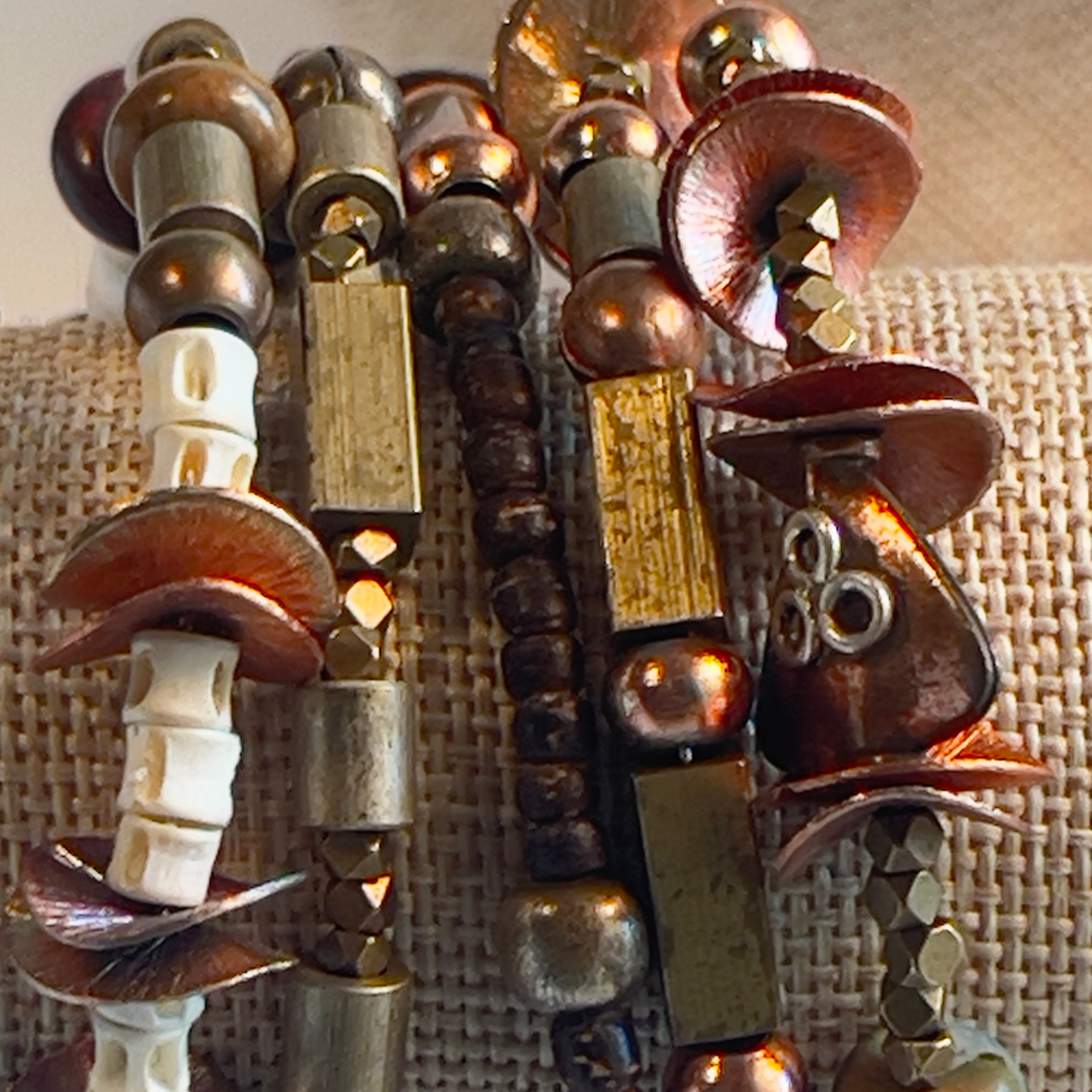 African style bracelet with hand-painted square ceramic bead, bold brass beads, cream bone spacers, square rectangle brass beads, copper round beads, and shiny textured copper flat spacers. Pair with a big copper medallion. Silver metal, one size fits all.