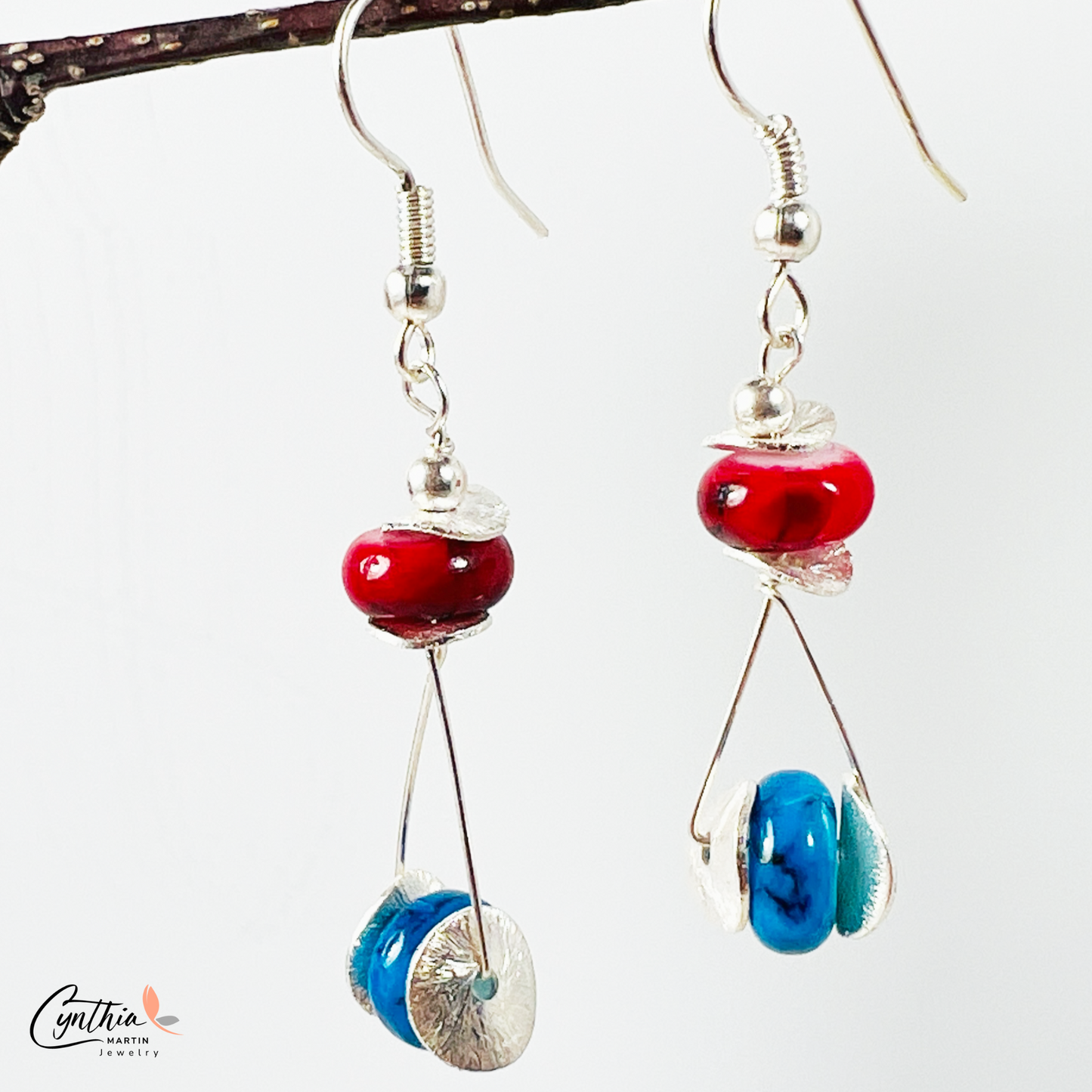 Playful earrings featuring blue beads that wink among red, adding subtle sparkle and charm.
