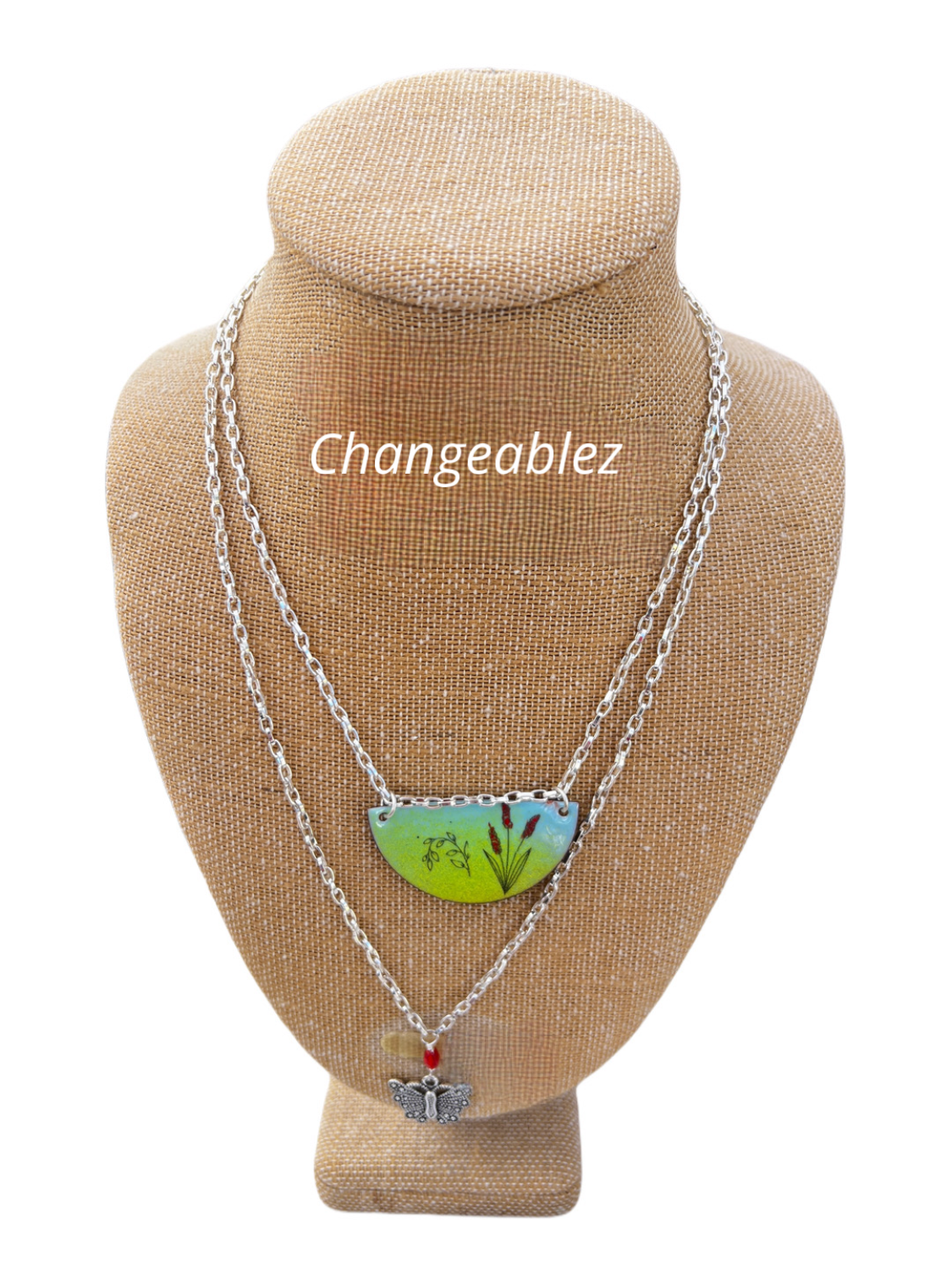 Multi-strand necklace with crescent-shaped enameled centerpiece, butterfly accent, and dark green beads, featuring an easily adjustable design with magnets.