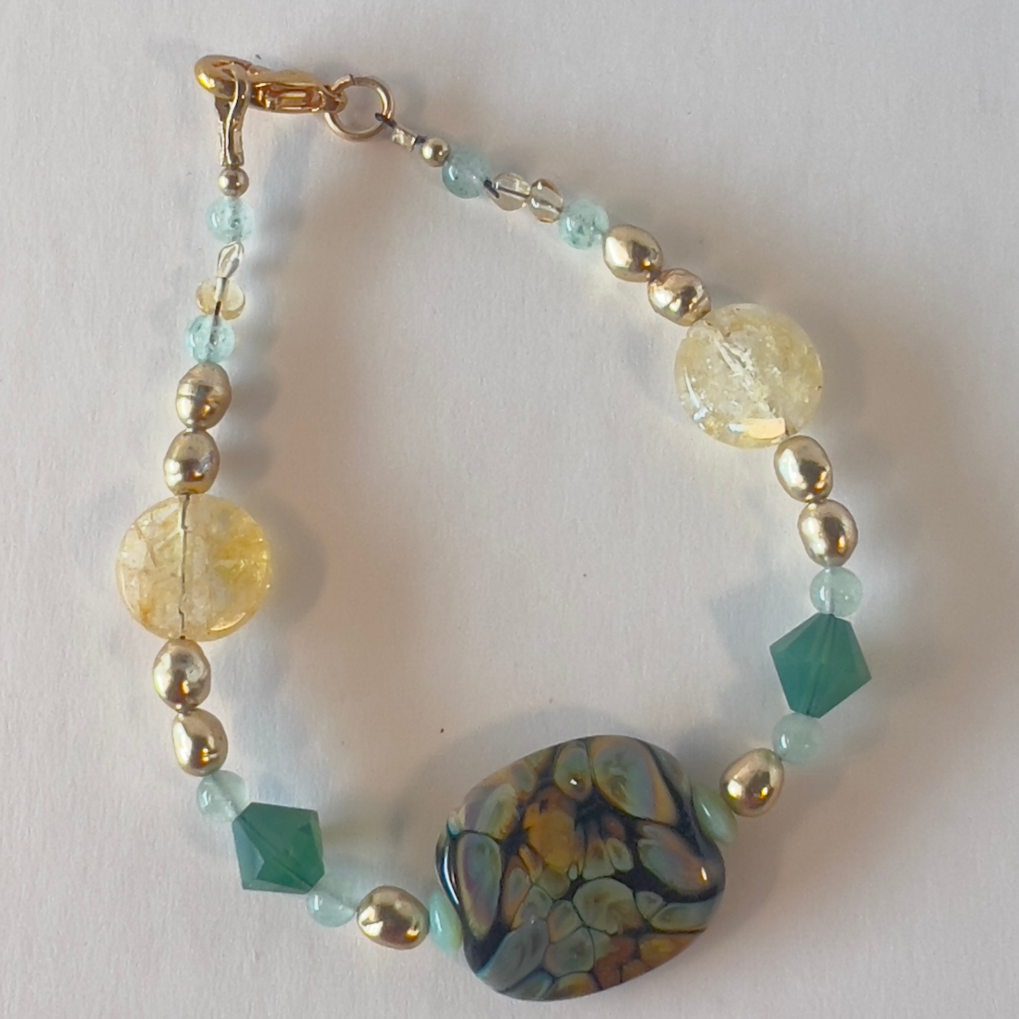 "Look At Me?" These blended colors of subtle pale yellow, transparent aquamarine, and a highly polished hand-made bead are made to be worn—the two 6mm opaque green bicones top this focal bead off so well.