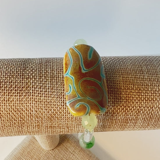 Transparency is the theme here. Quiet, sweet, with green sandstone beads, pale green heart-shaped beads, and beautiful ice green tube beads with splashes of honey-colored rondelles. The focal bead is designed by a dear friend, and I am so glad to be able to show it off to her. Gold metal, wrist size 7 1/2 in.