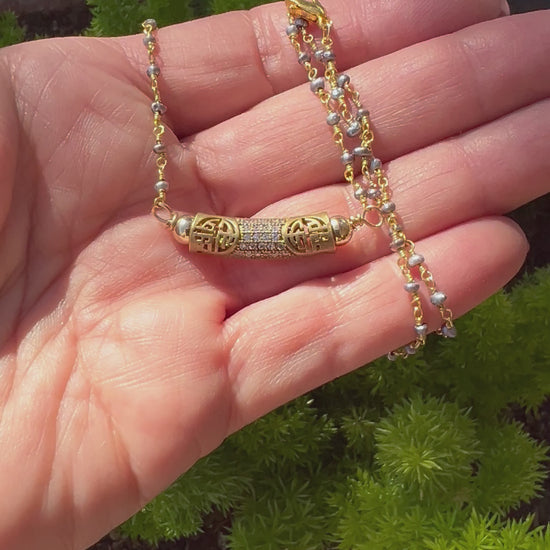 Tiny gold beaded chain with antiqued brass pave tube pendant, blending vintage charm with elegant simplicity.