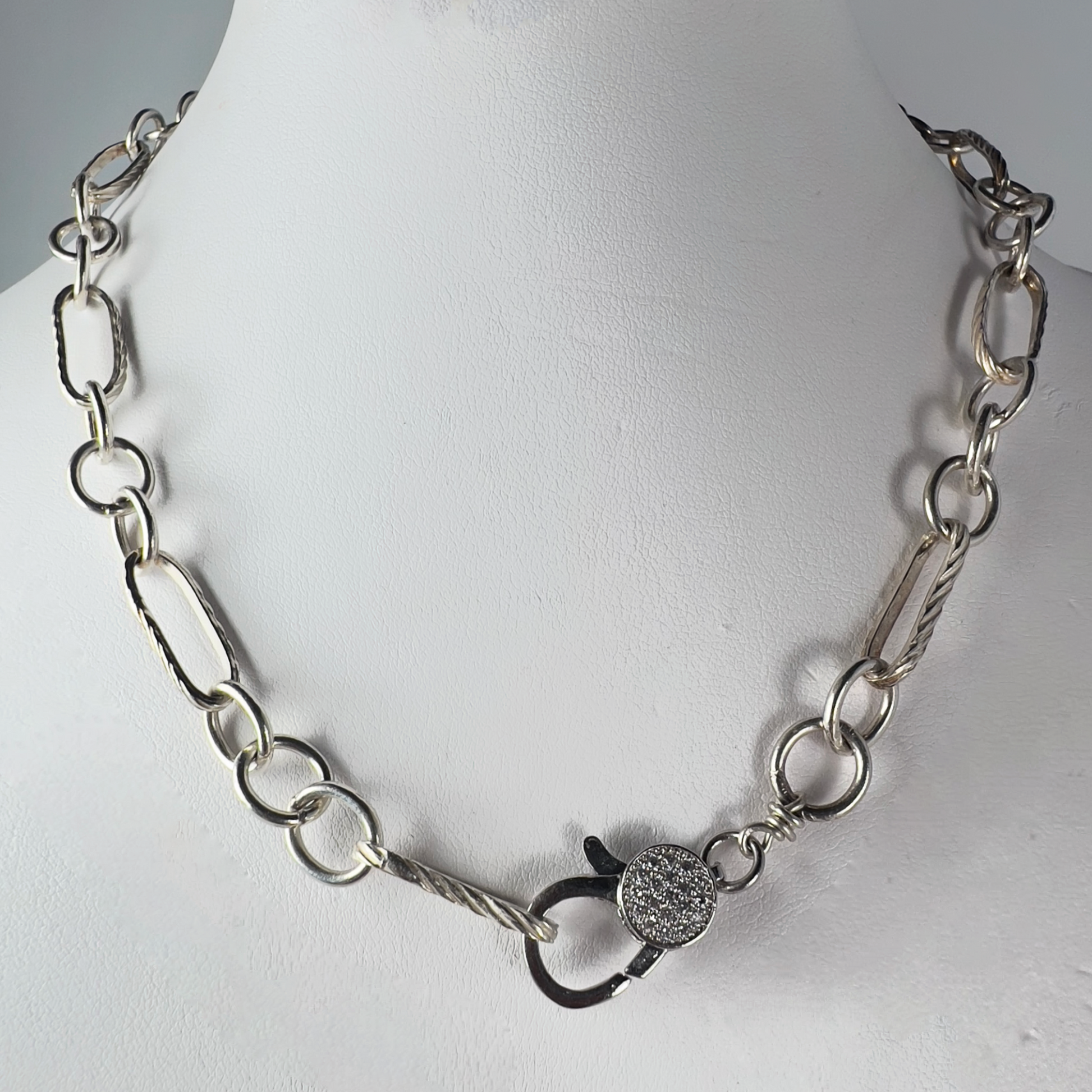 Trendy multi-link twisted chain with oval and round links in sterling silver, featuring a pave lobster clasp.