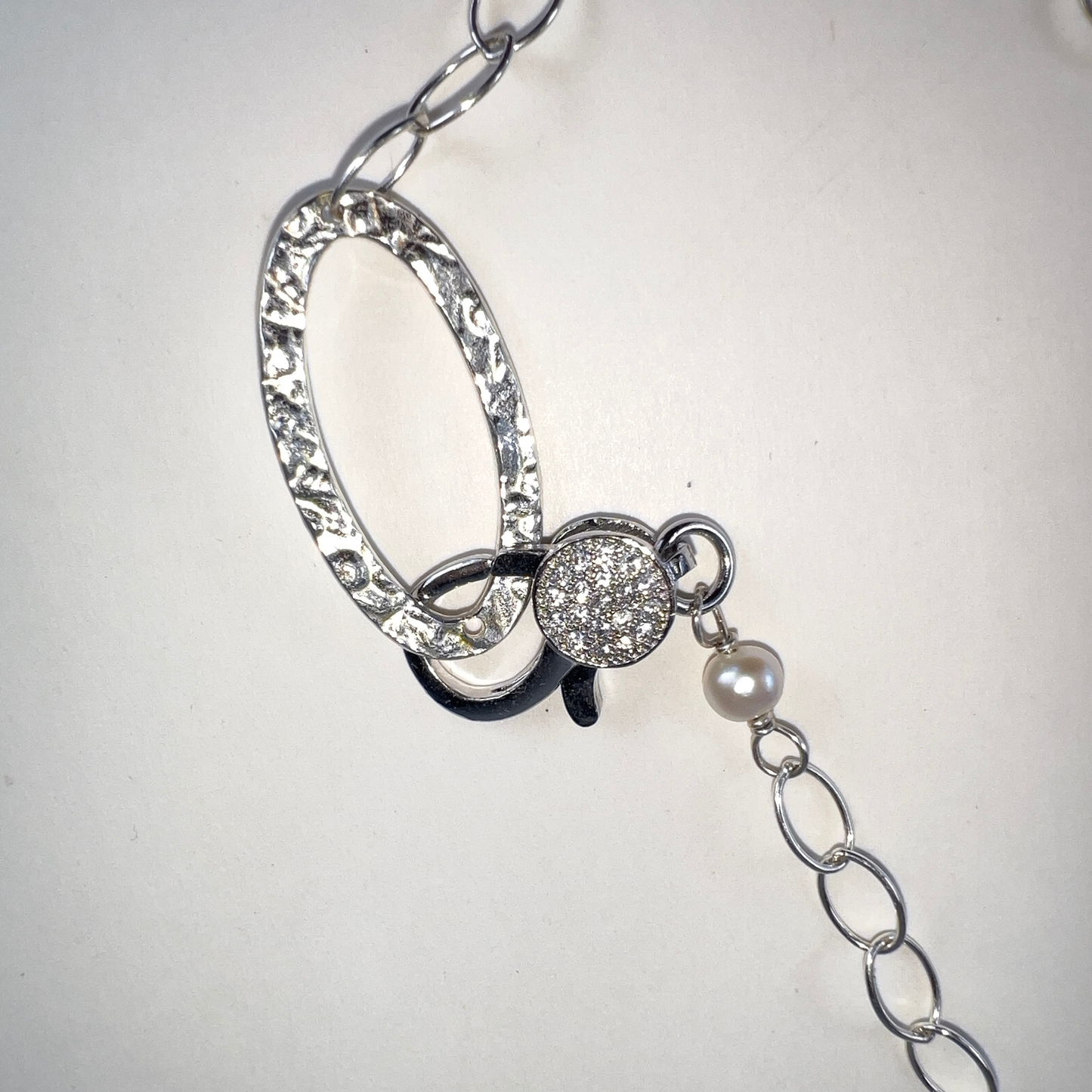 Trendy multi-link twisted chain with oval and round links in sterling silver, featuring a pave lobster clasp.