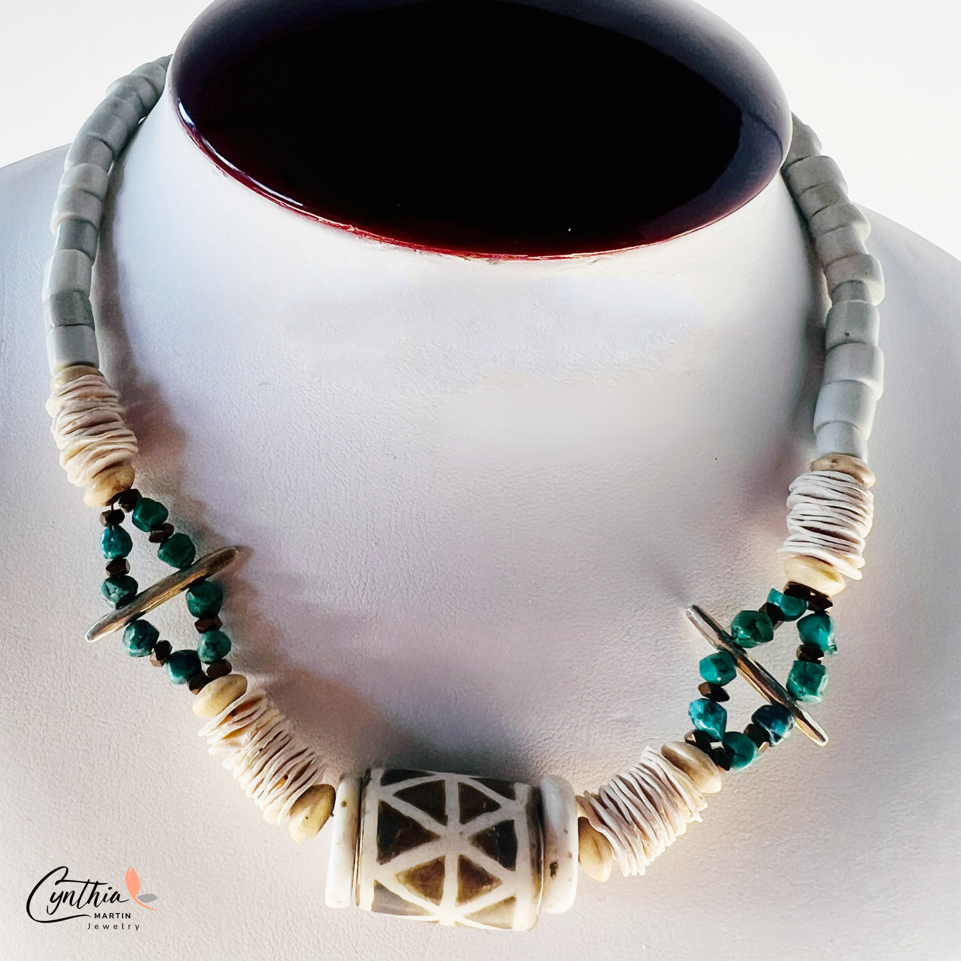 Bold necklace featuring a hand-painted African tribal wooden focal bead, turquoise nuggets, and bone Heishi beads, 15 inches with a 2-inch extender.
